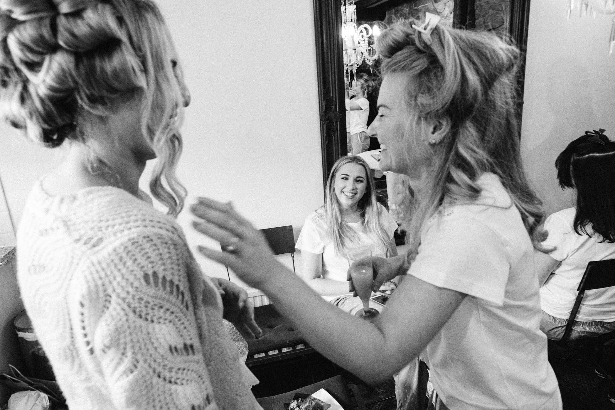 Black and white shot of bridal party sharing a joke whilst drinking