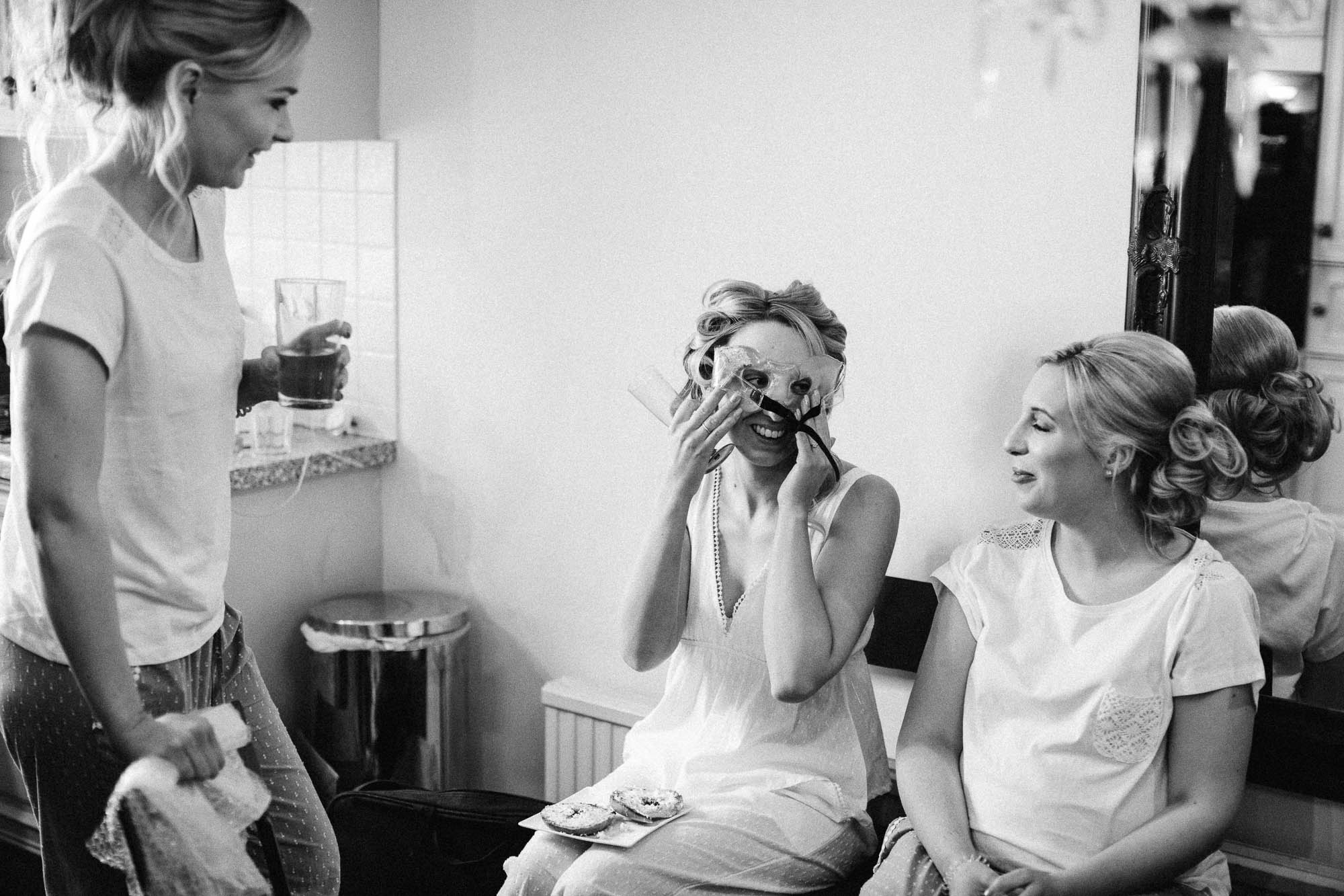 Bride tries on mask that bridal party have given her to wear on morning on wedding