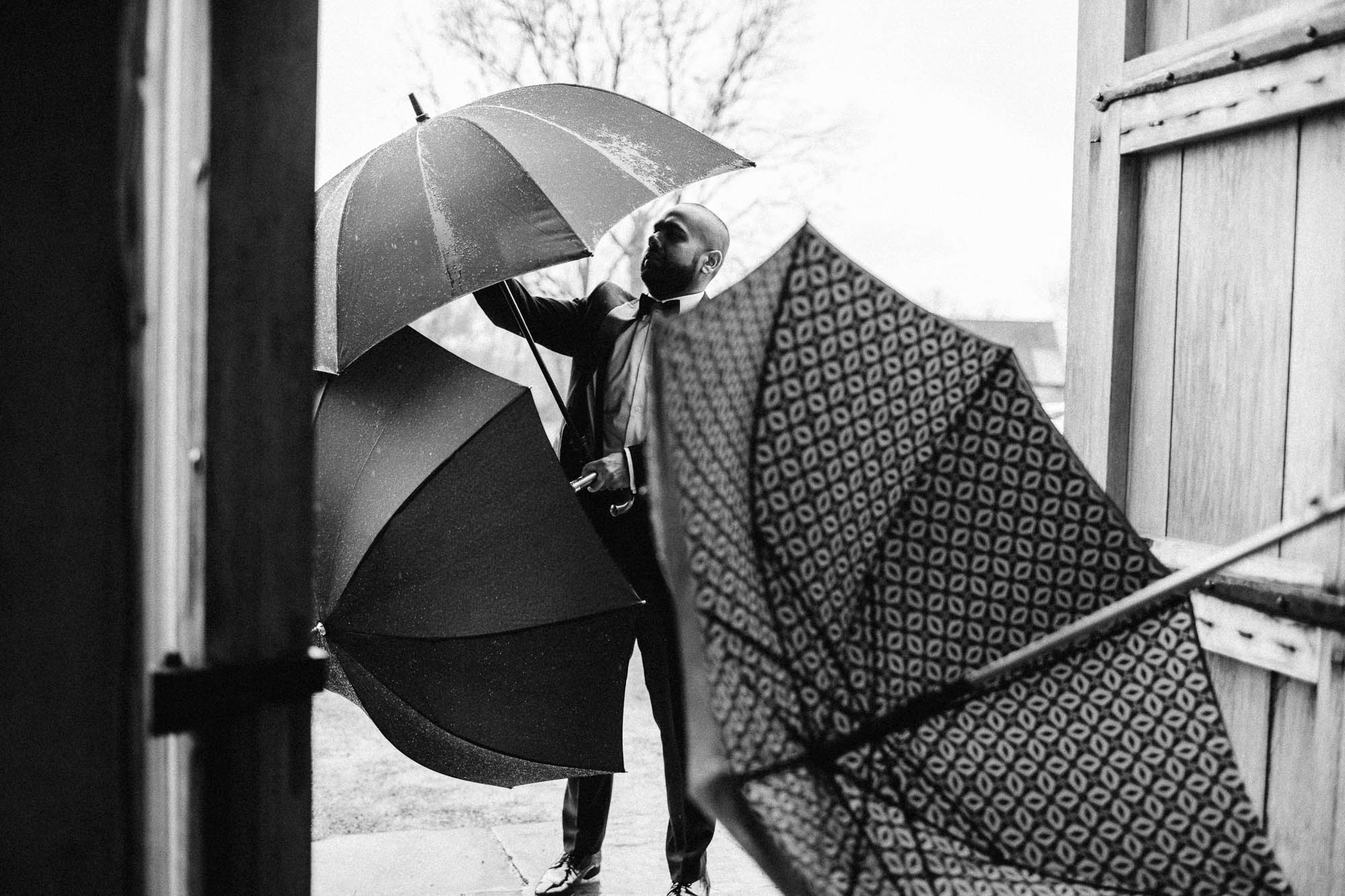 Black and white shot of wedding guests putting up umbrellas