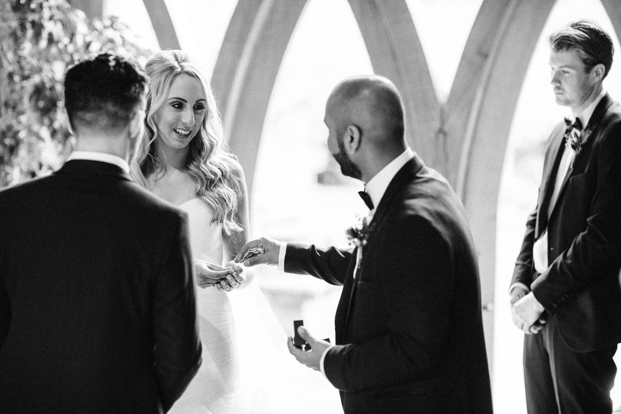 Black and white shot of Best man giving bride the ring at wedding ceremony