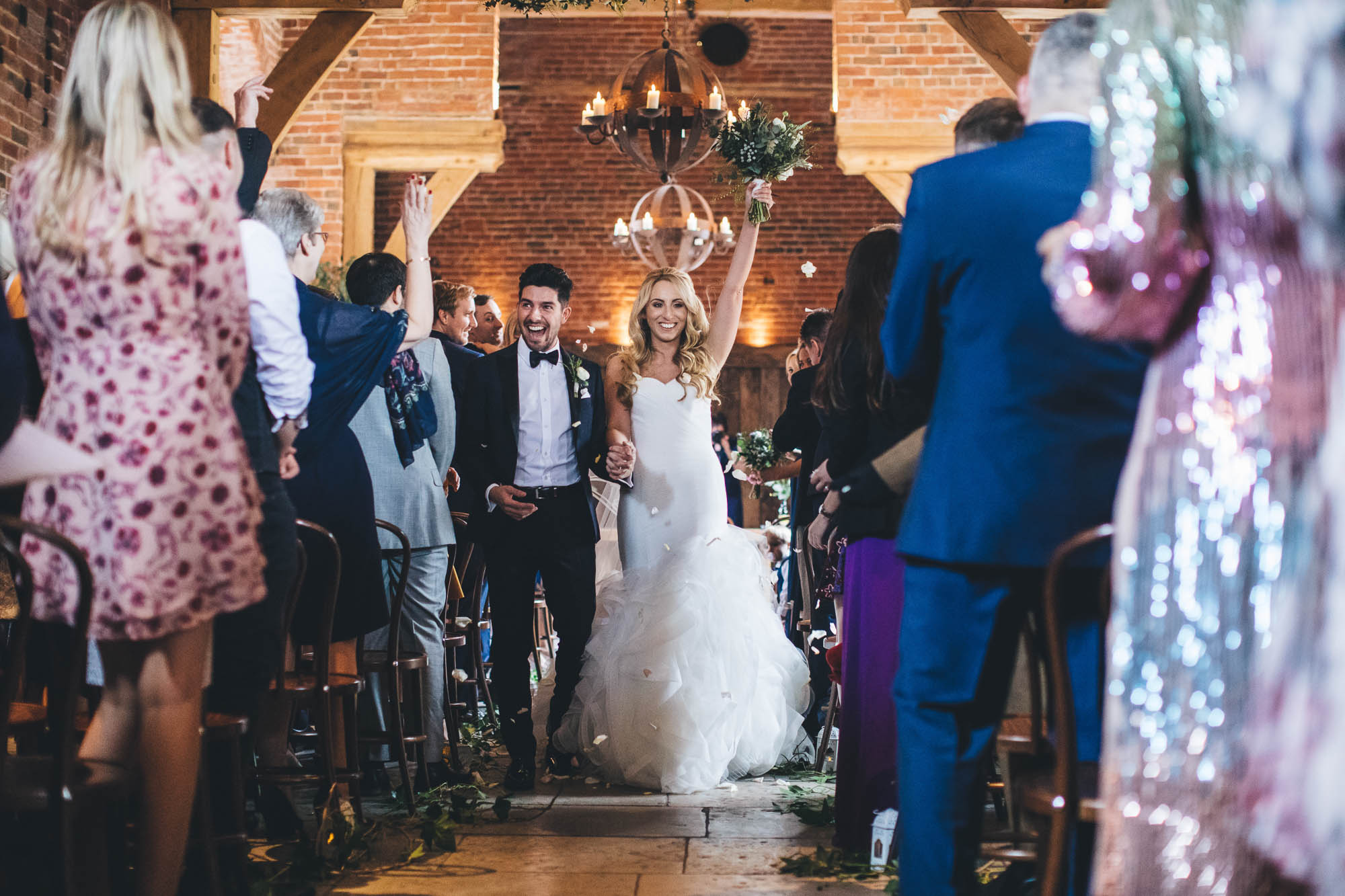 Wedding guests throw confetti over happy newlyweds as they walk back down the aisle