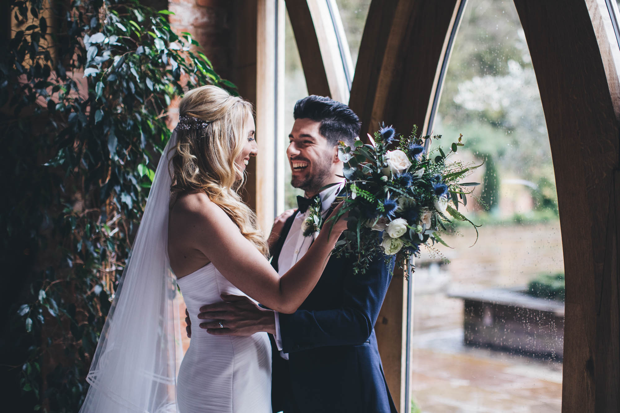 Newlyweds hold each over lovingly infront of elaborate large framed windows