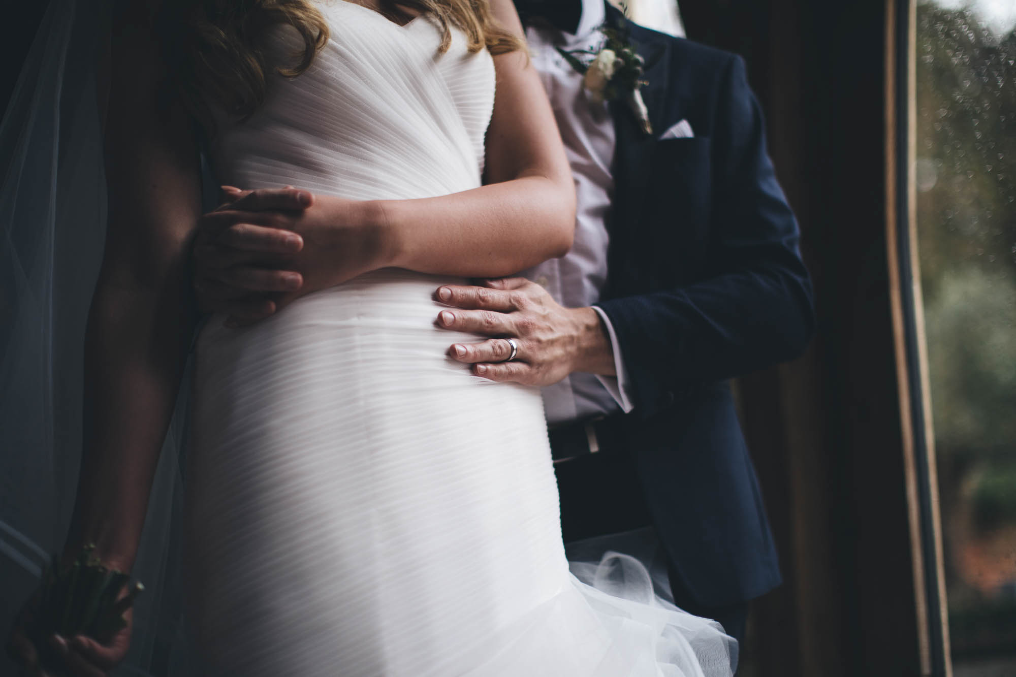 Close up shot of newlyweds holding hands round Bride's waist