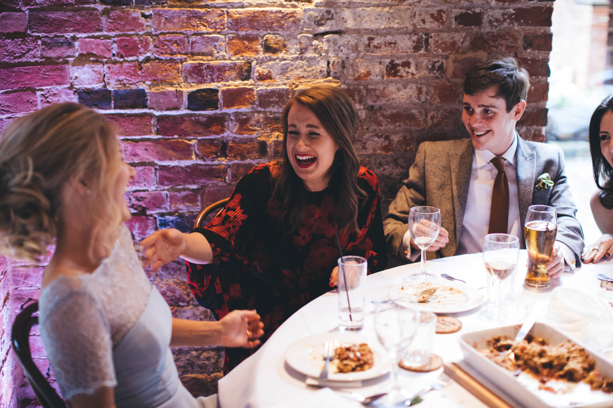 Wedding guests share a hilarious joke at reception dinner