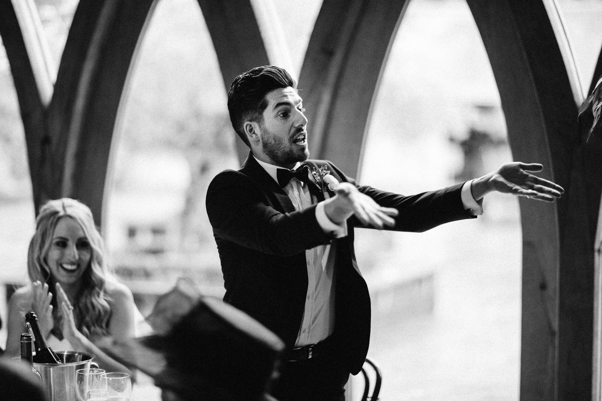 Black and White shot of Groom gesturing at Best man after funny wedding speech