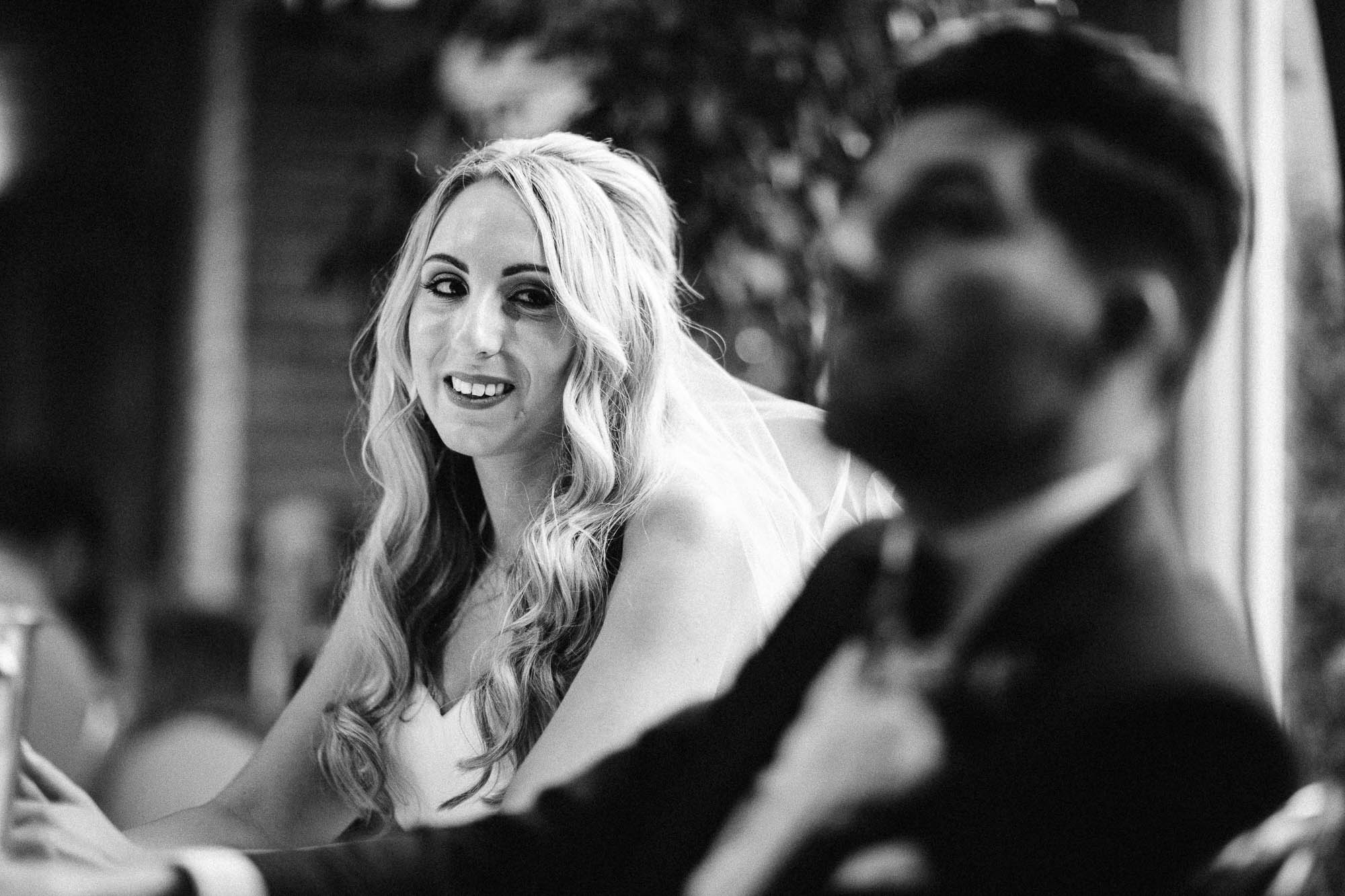 Bride looks over to Groom knowingly during a wedding speech joke