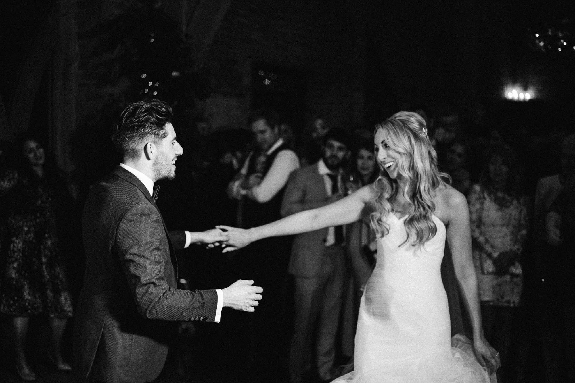 Bride and Groom smile at each other as they have their first dance in rustic barn
