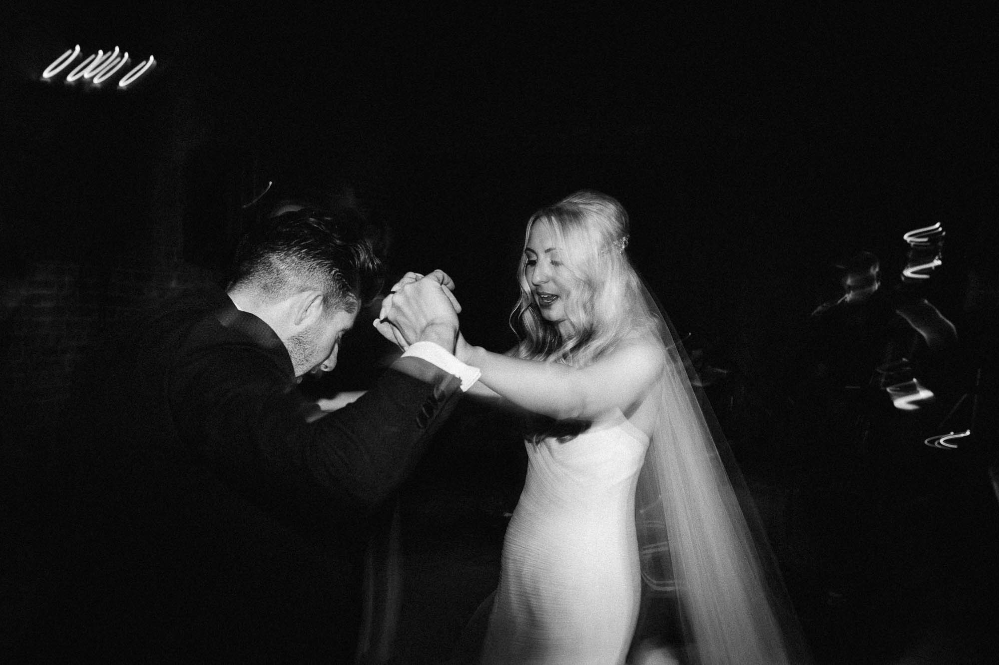Black and white shot of newlyweds dancing on dancefloor at end of the night
