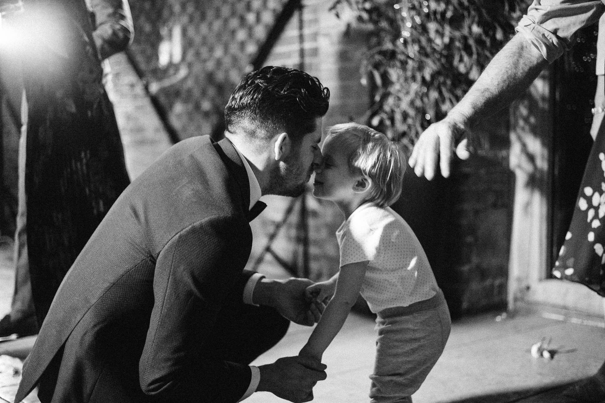 Black and white shot of bridegroom and young relative nuzzling each other's nose on the dancefloor