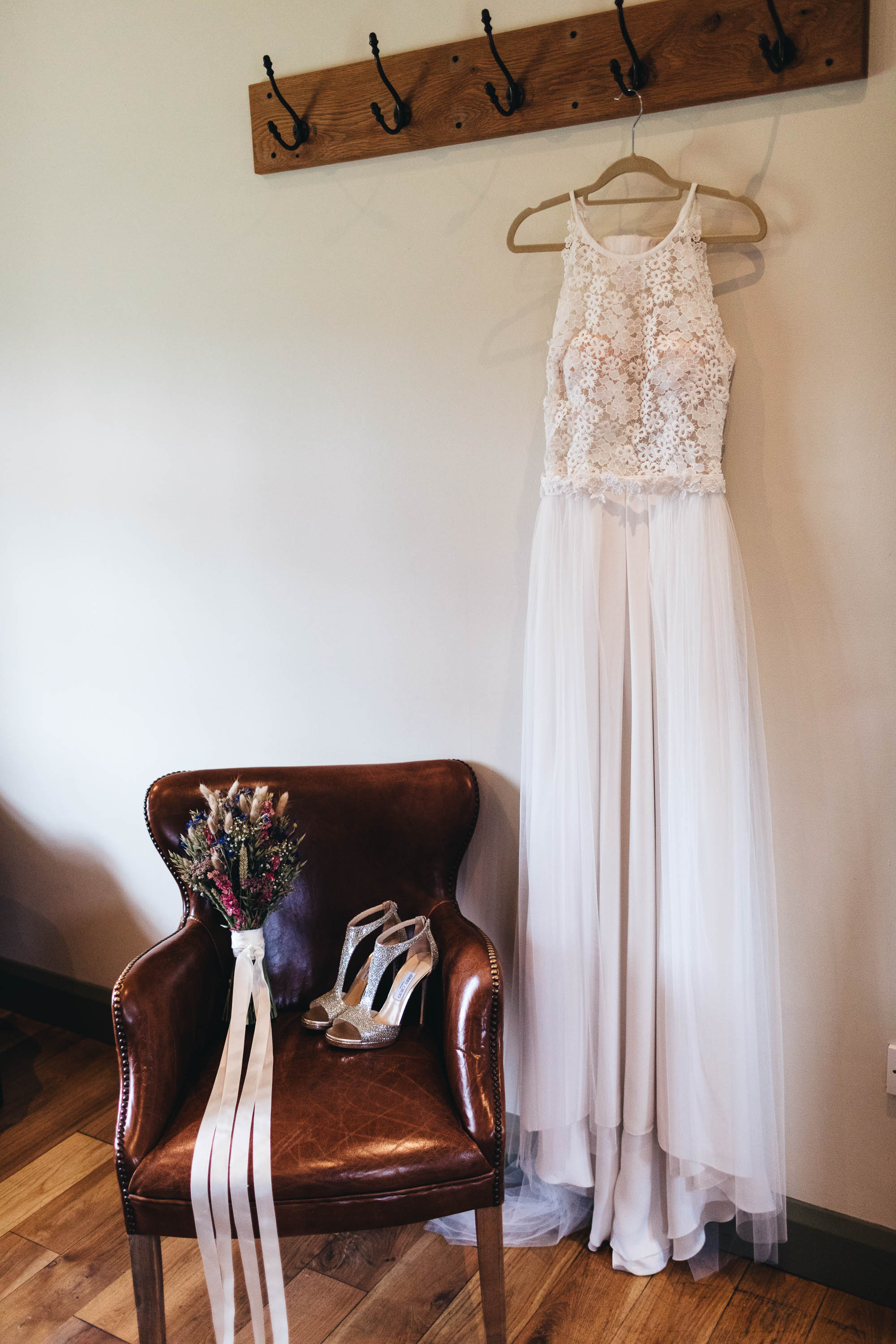 Wedding dress hung up with shoes and bouquet on chair waiting for Bride to pick up
