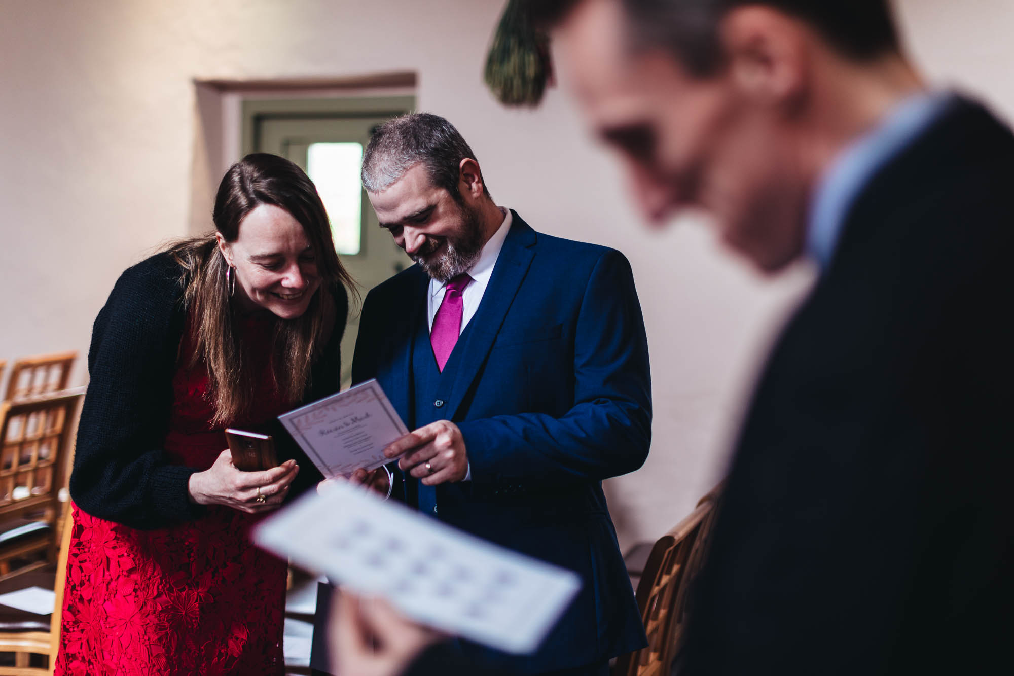 Wedding guests look at the order of ceremonies stationery for wedding