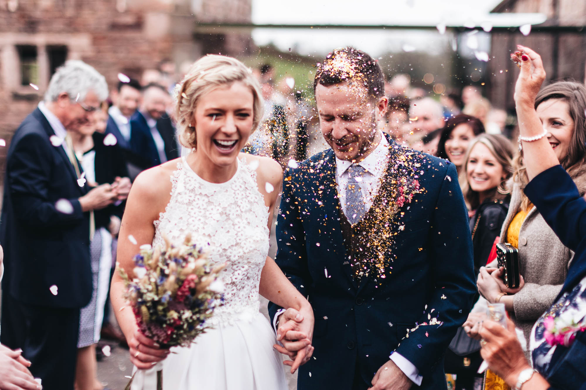 Groom get covered in glitter as wedding guests throw confetti at the happy couple