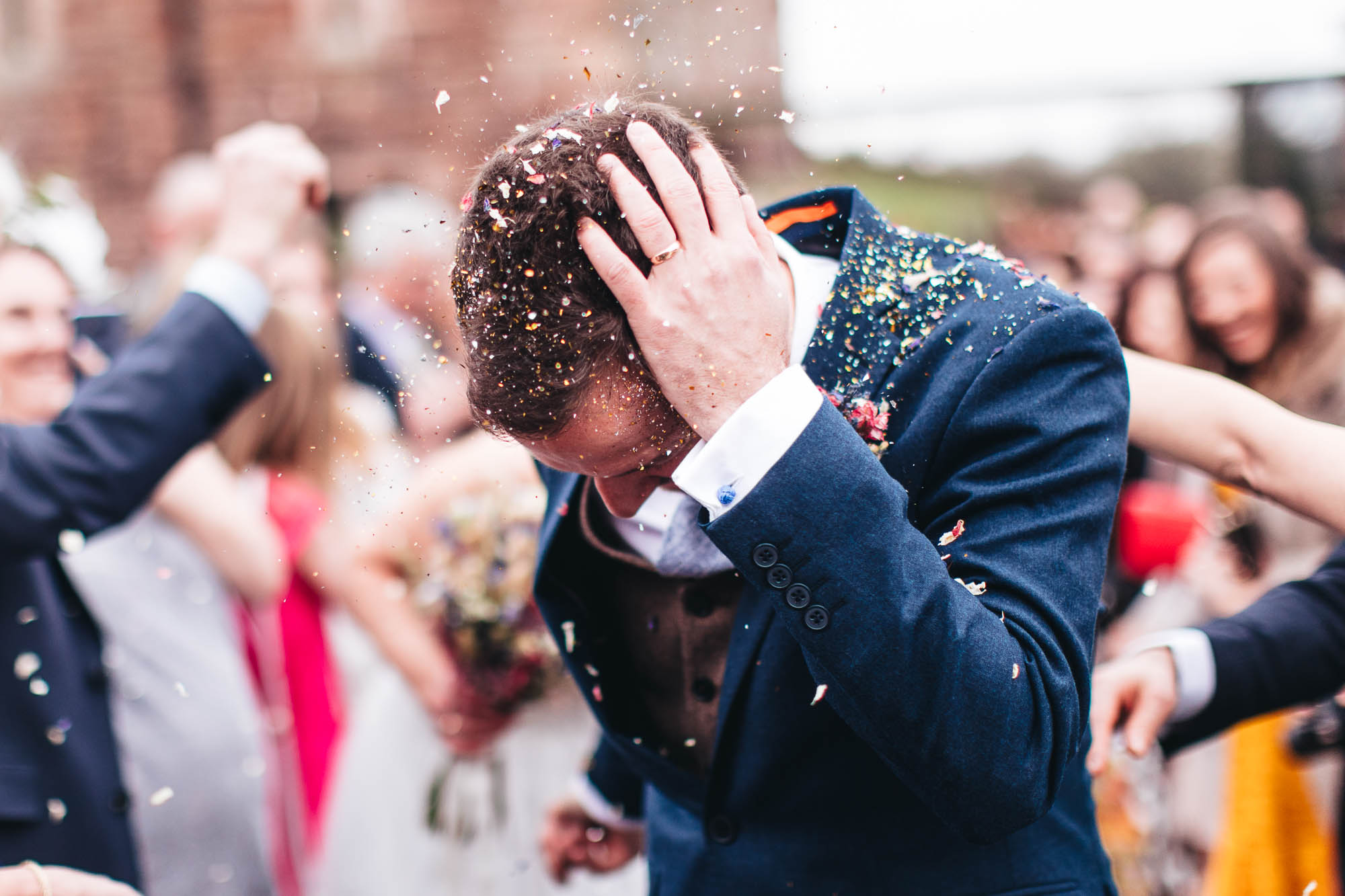 Groom brushes the excessive amounts of glitter out of his hair just after wedding