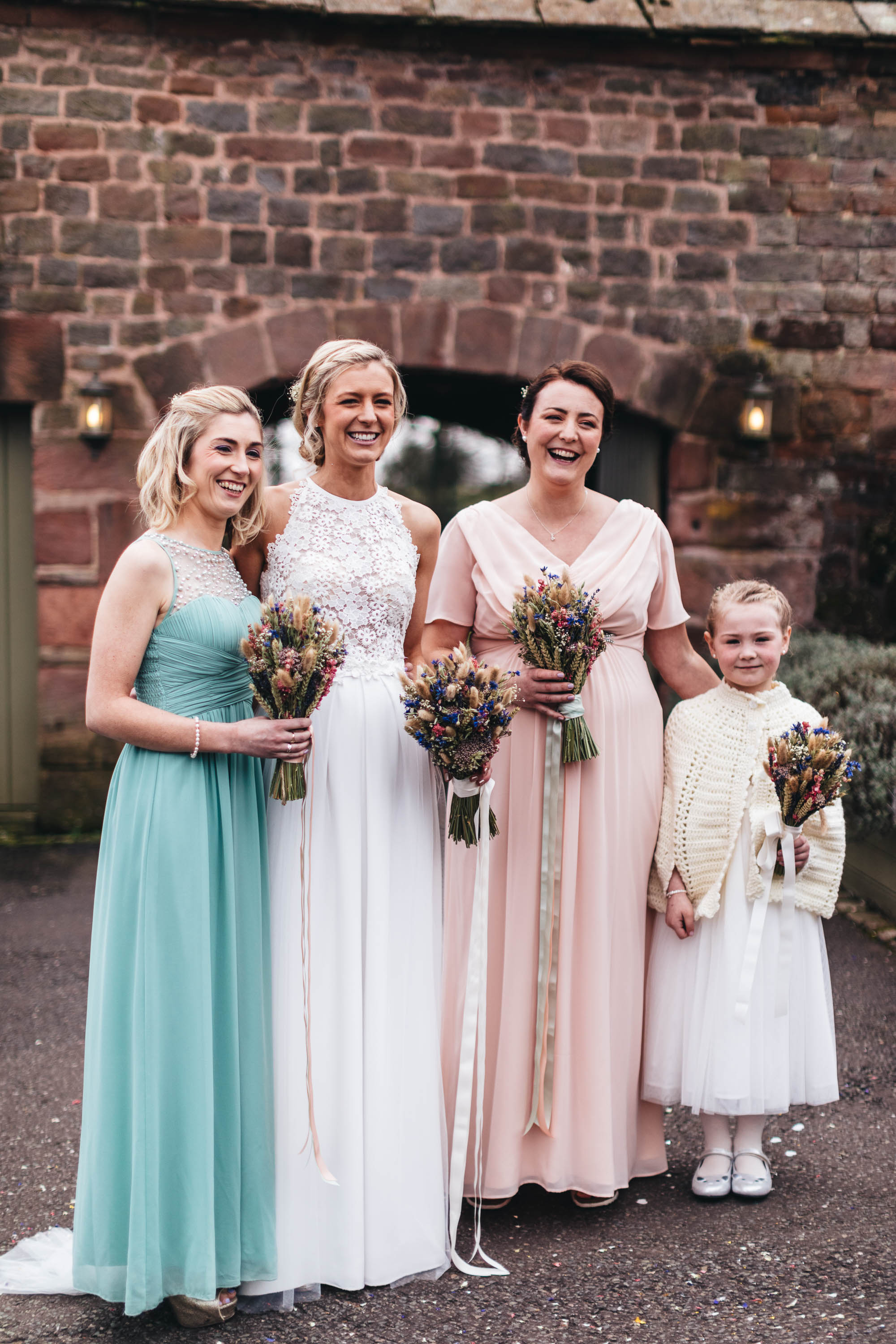 Bridal party and flower girl pose for photo outside The Ashes Wedding Venue