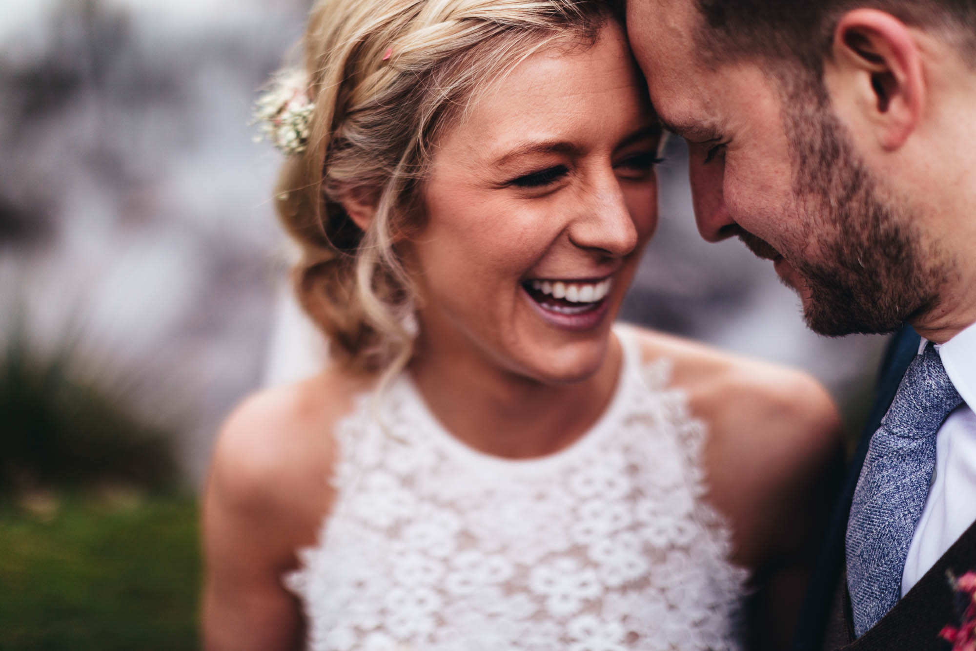Close up shot of intimate moment between Bride and Groom amongst lush green grass