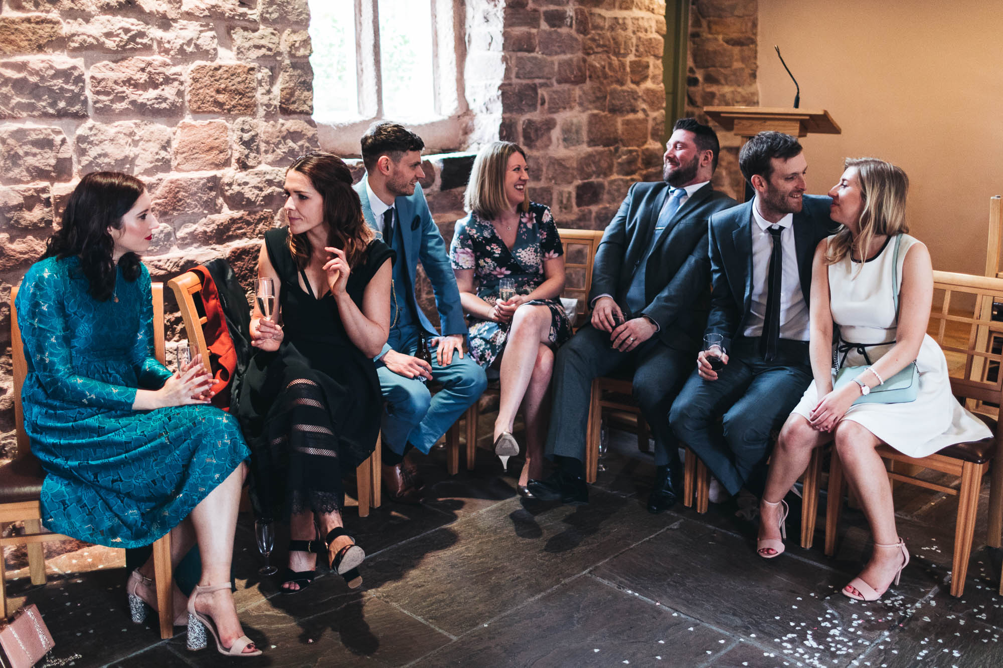 Group shot of young wedding guests enjoying a drink and chat after wedding ceremony
