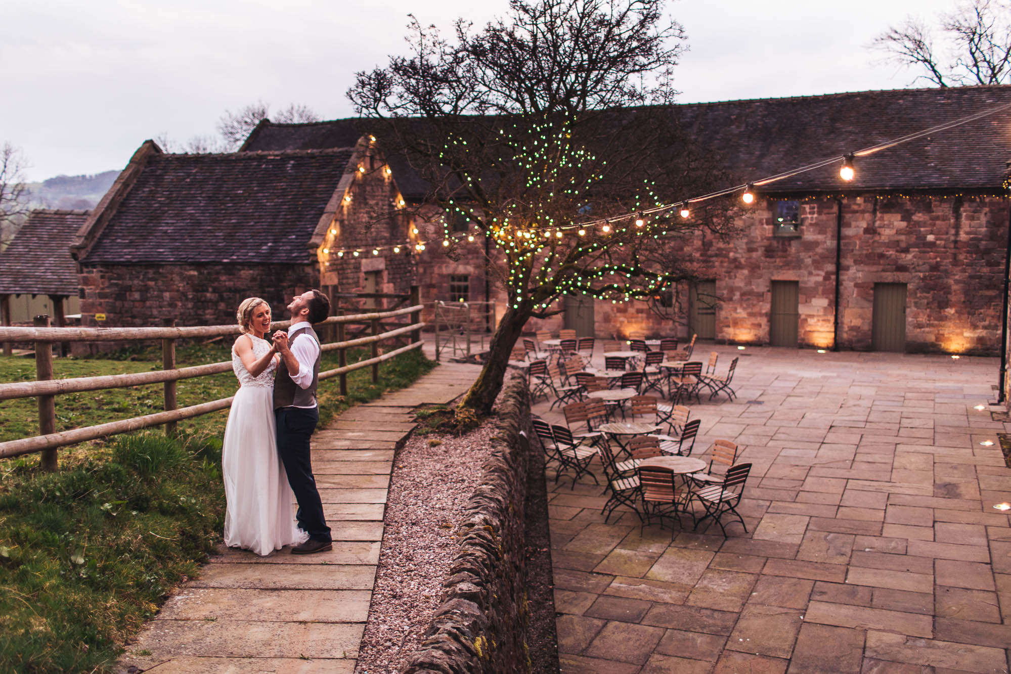Wide external shot of The Ashes Wedding Venue featuring a happy new couple dancing in front of fairy lights