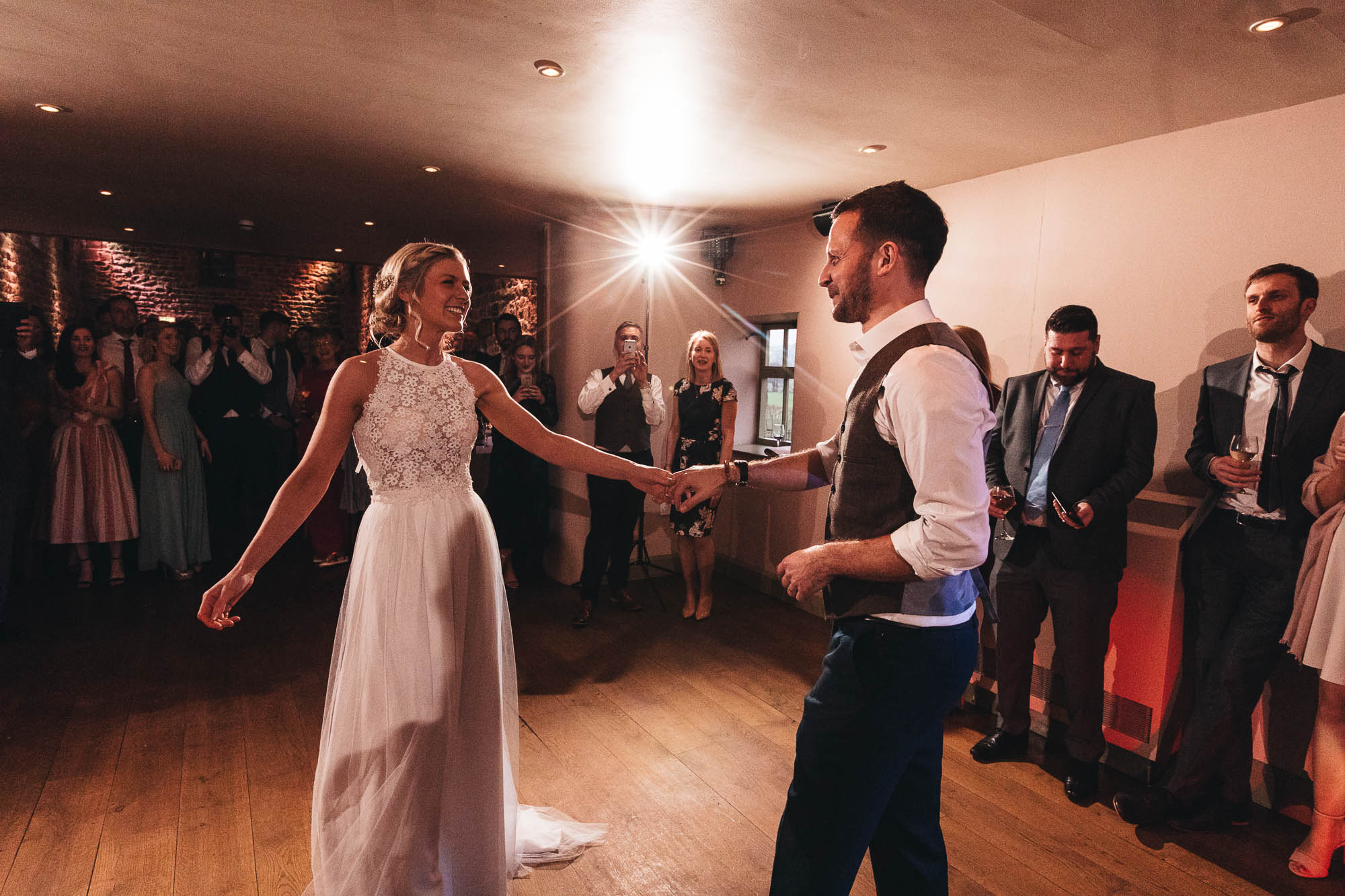Newlyweds share their first dance surrounded by happy wedding guests