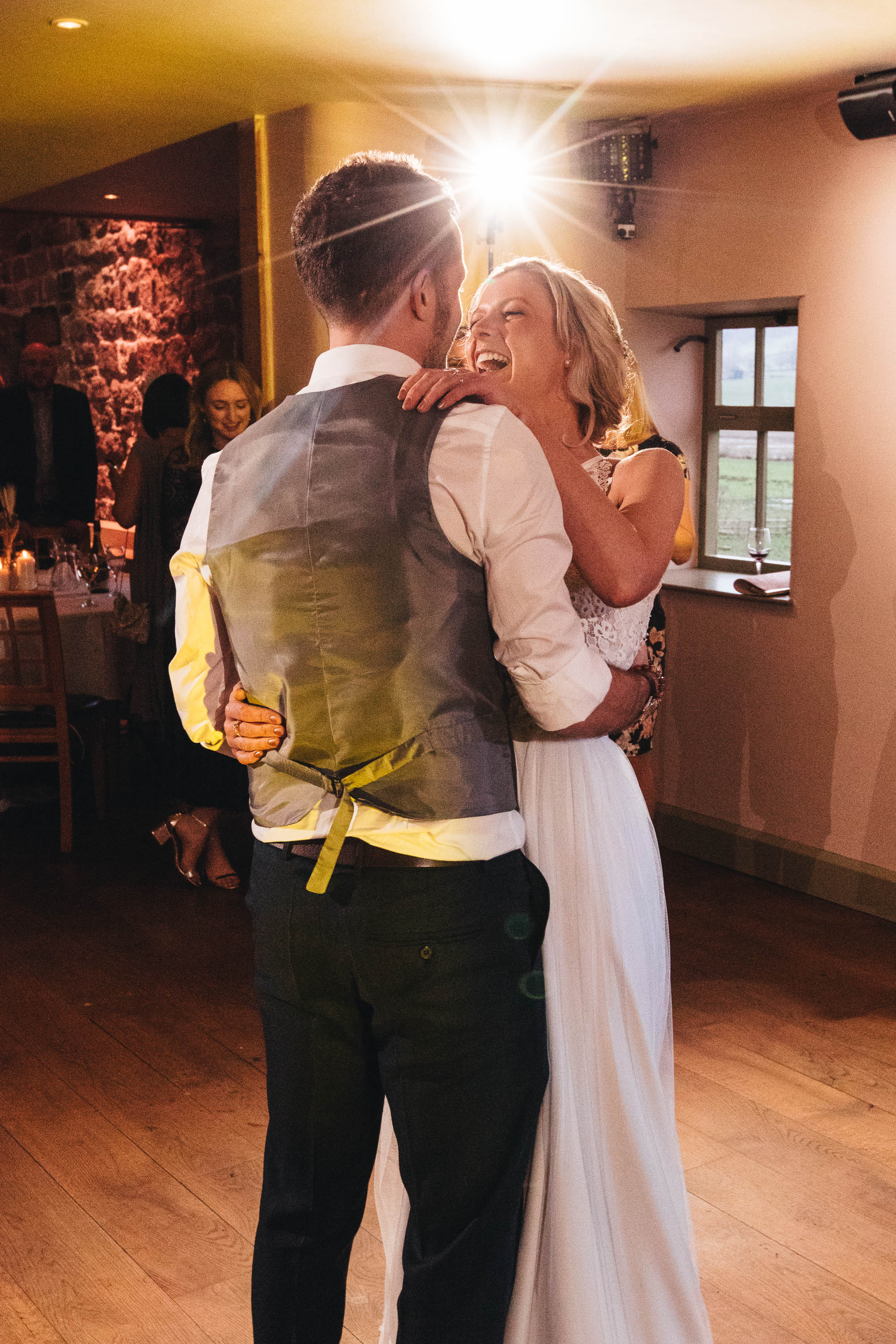 Bride laughs as the Groom holds her closer during first dance