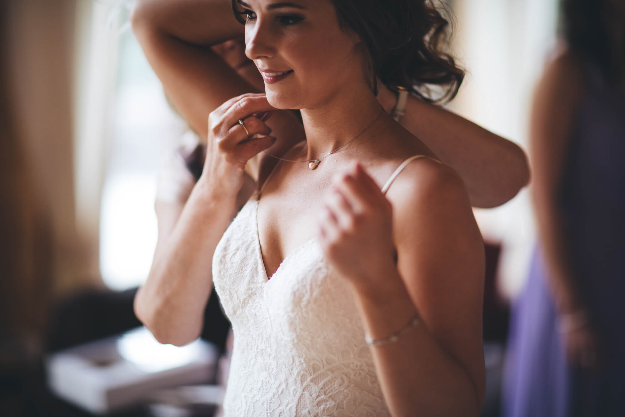CLOSE UP OF BRIDES NECKLACE BEING PUT ON