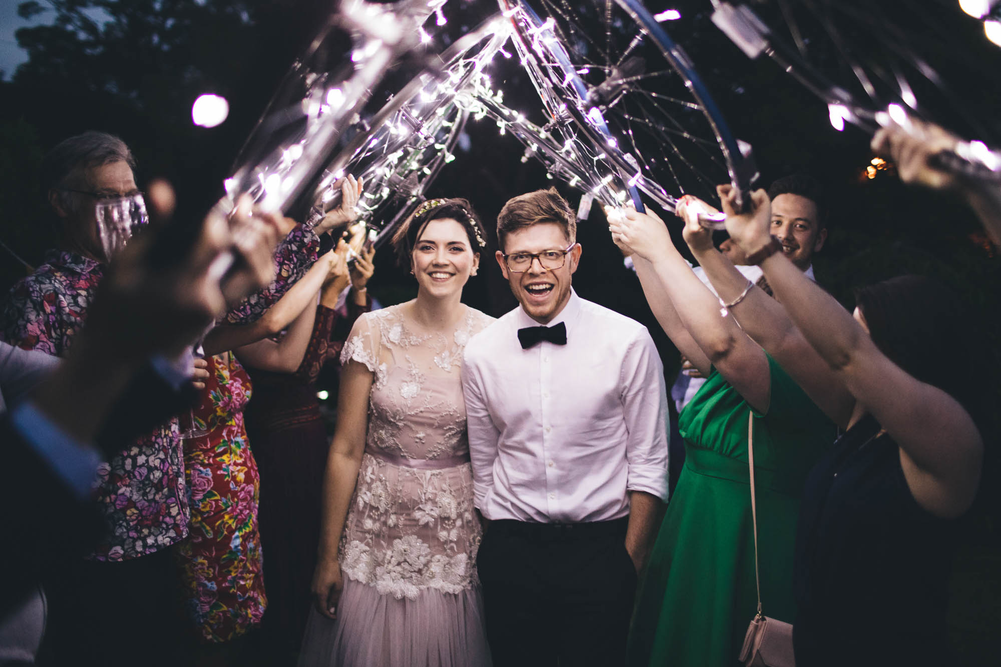 couple walk through arch made of bike wheels at night