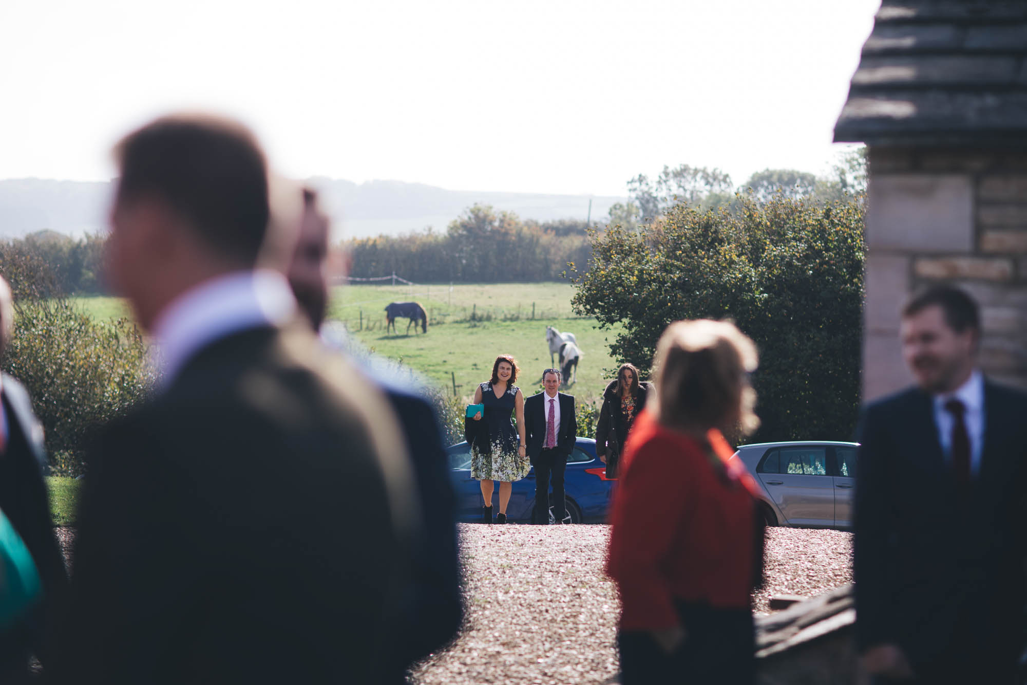 more wedding guests arive in the distance with farm background