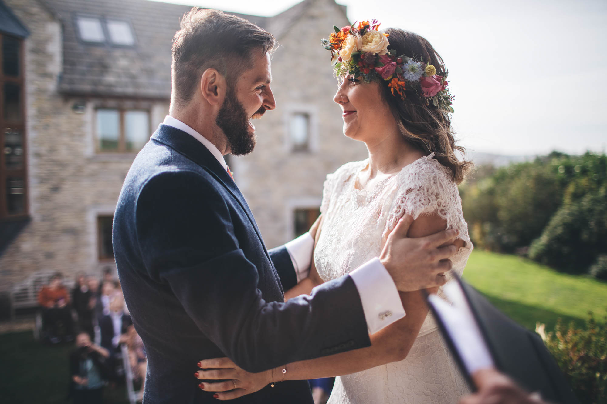 joyful and natural moment between the newly weds, groom has hold of brides arms and they smile at each other