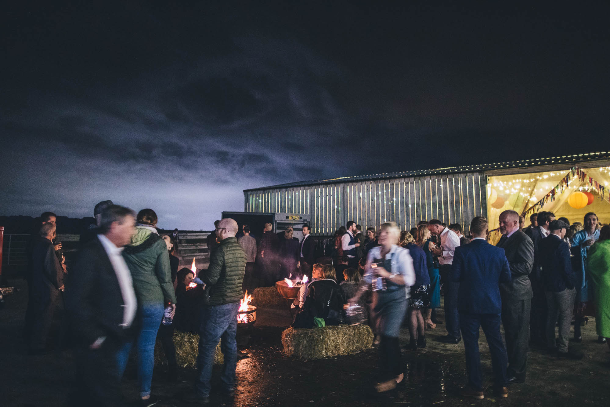 wedding guests outside at night and clouds are lit by the moon