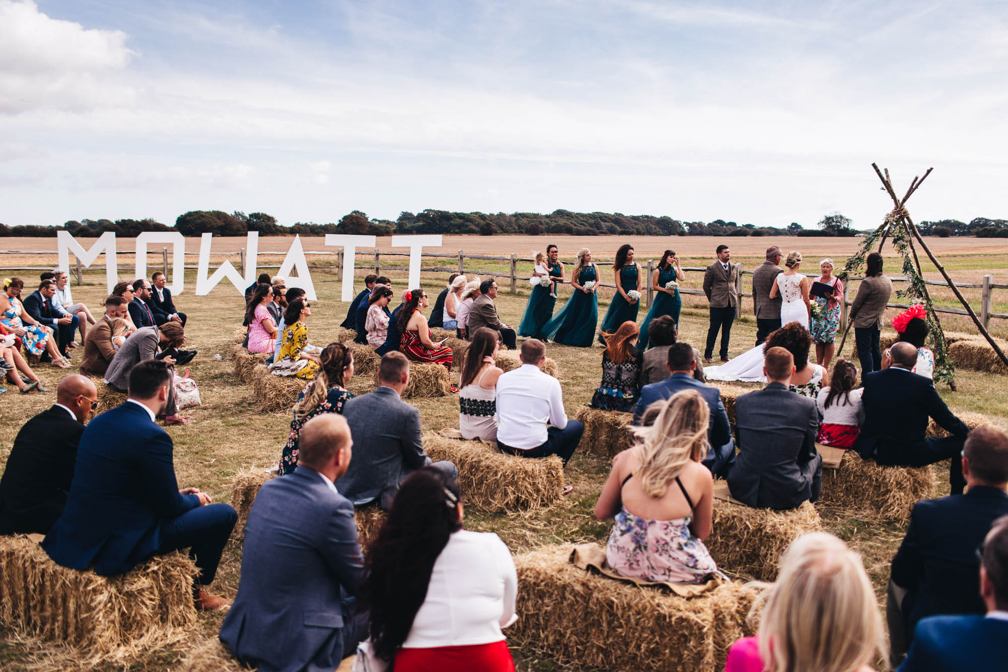 wide angle scene of wedding guests on hay bales and the wedding party waiting for the ceremony