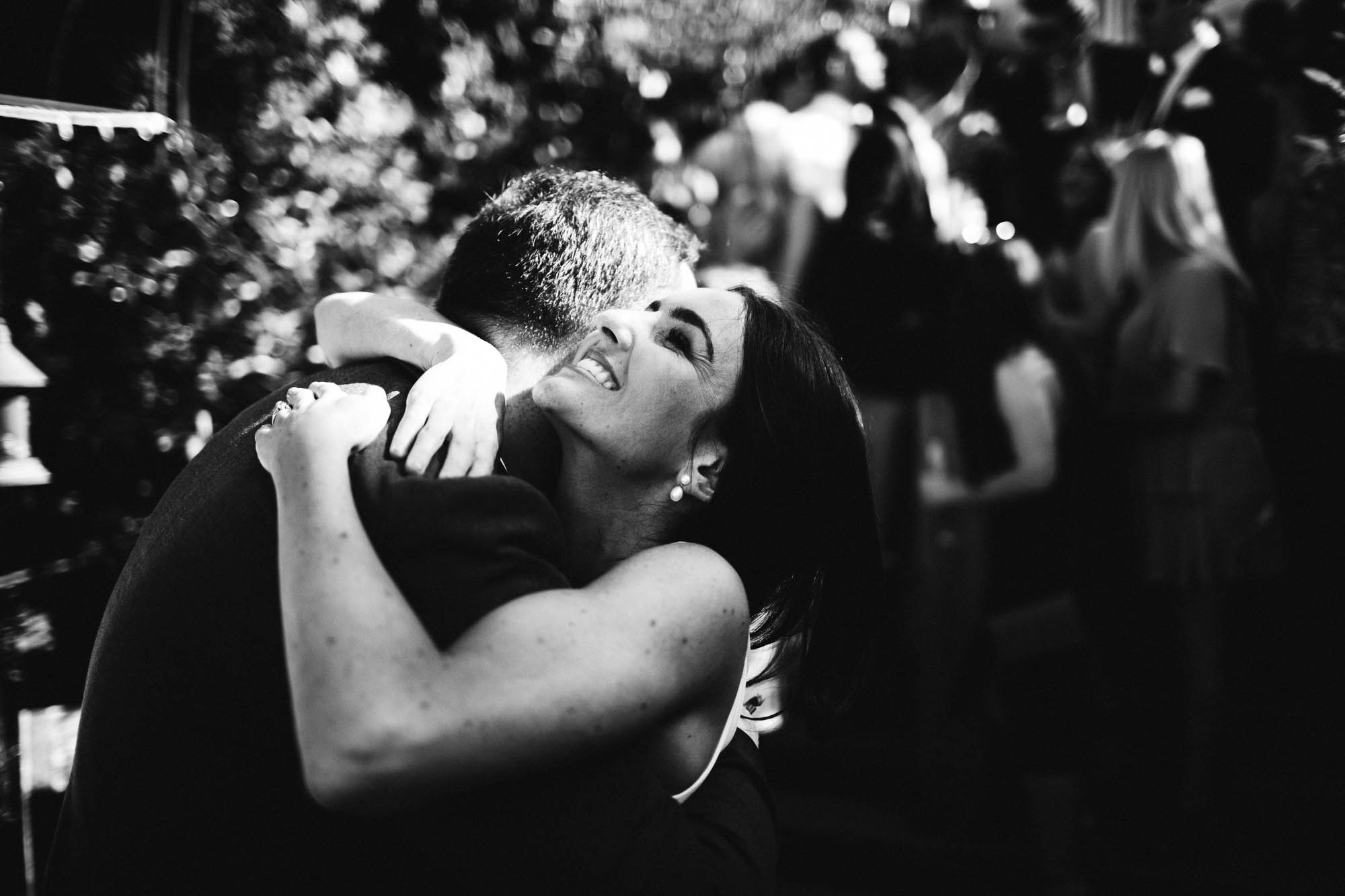 black and white shot of bride hugging a guest