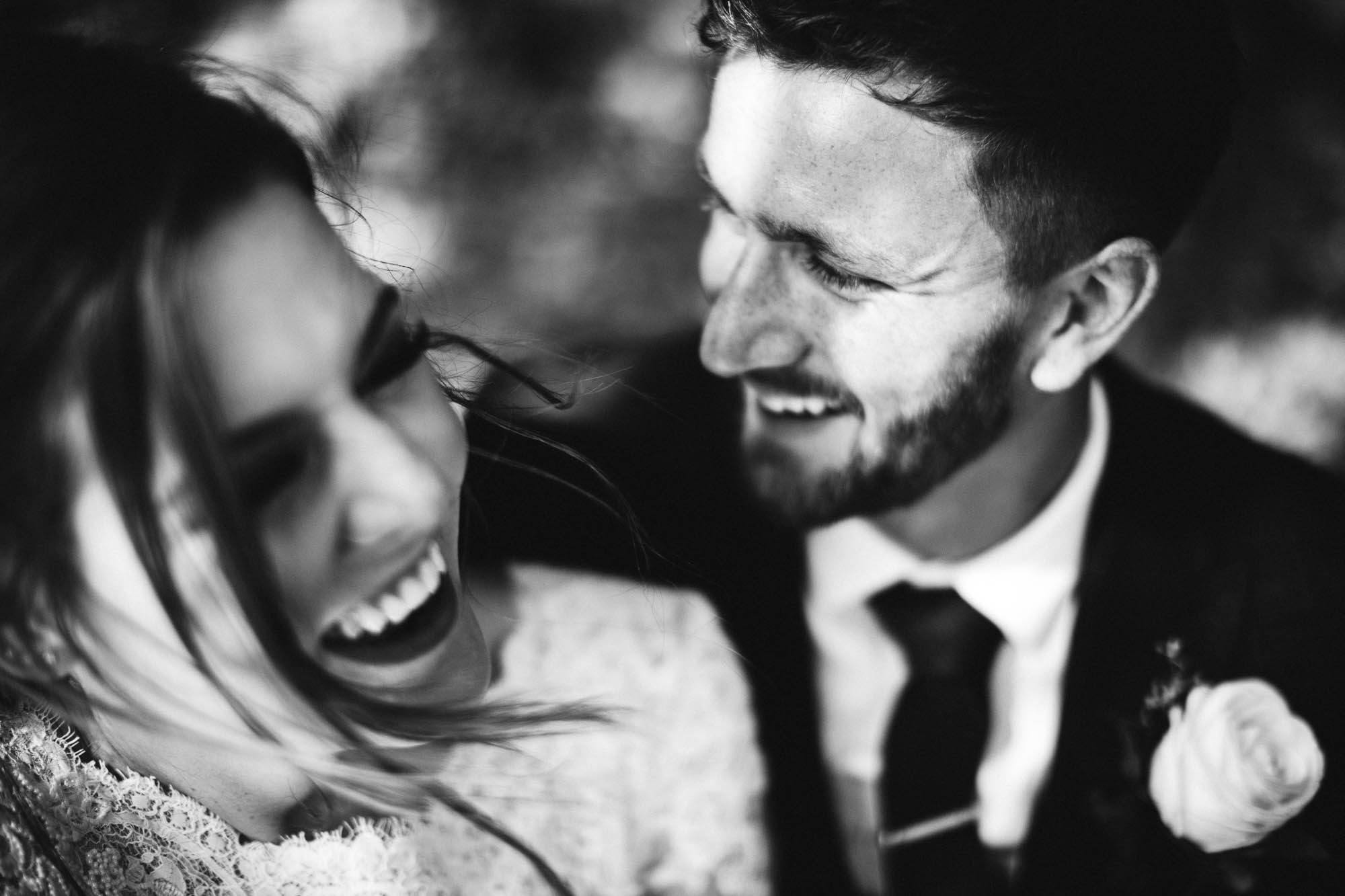 close up shot of couple laughing together covered in dappled sunshine