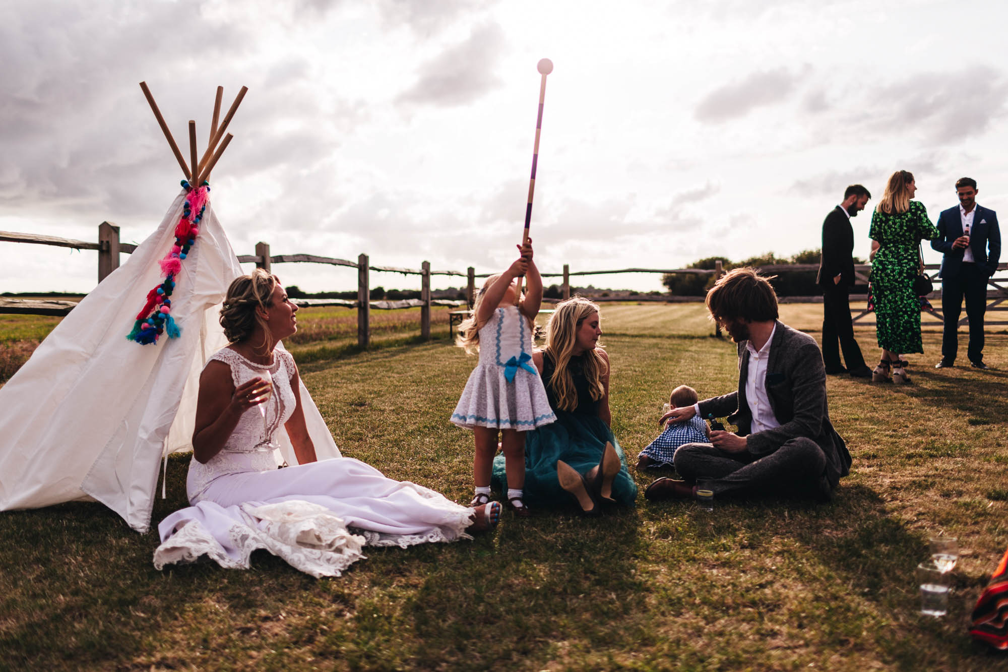 brides sat next to child tent while the kids play around her