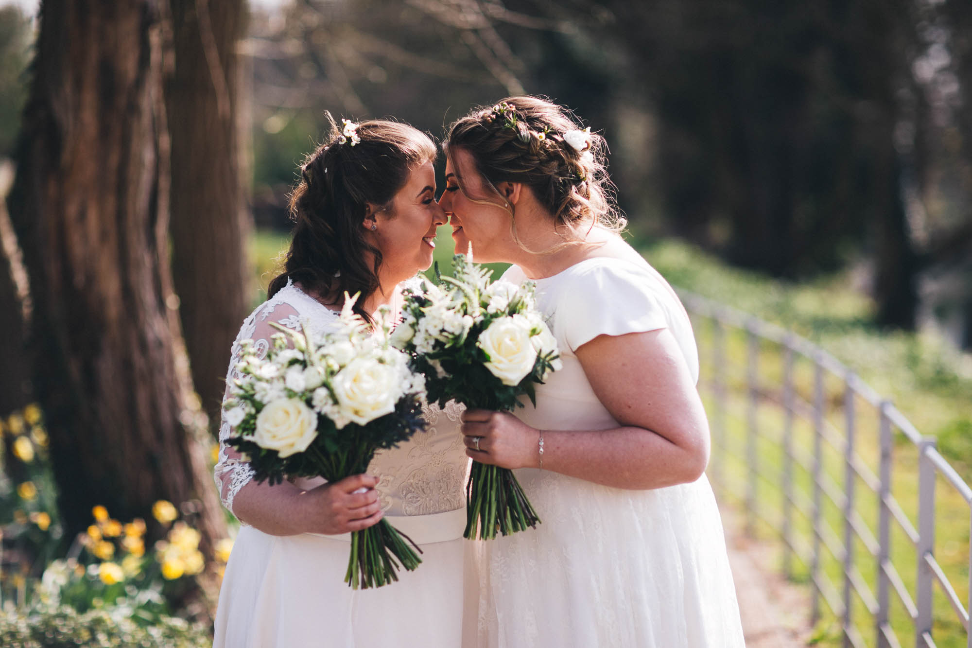 two lesbians in gay wedding touch their noses in a romantic moment