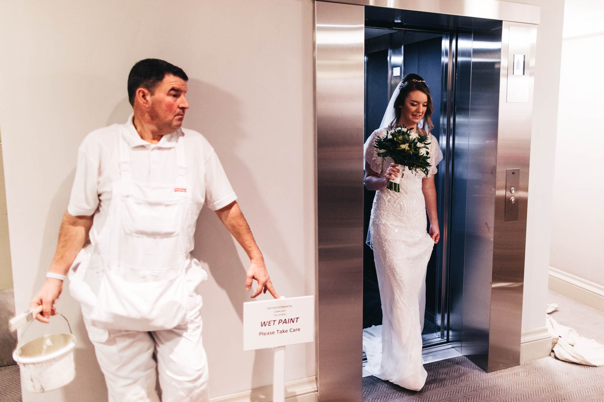 bride comes out of lift to find decorator there with paint brush in hand