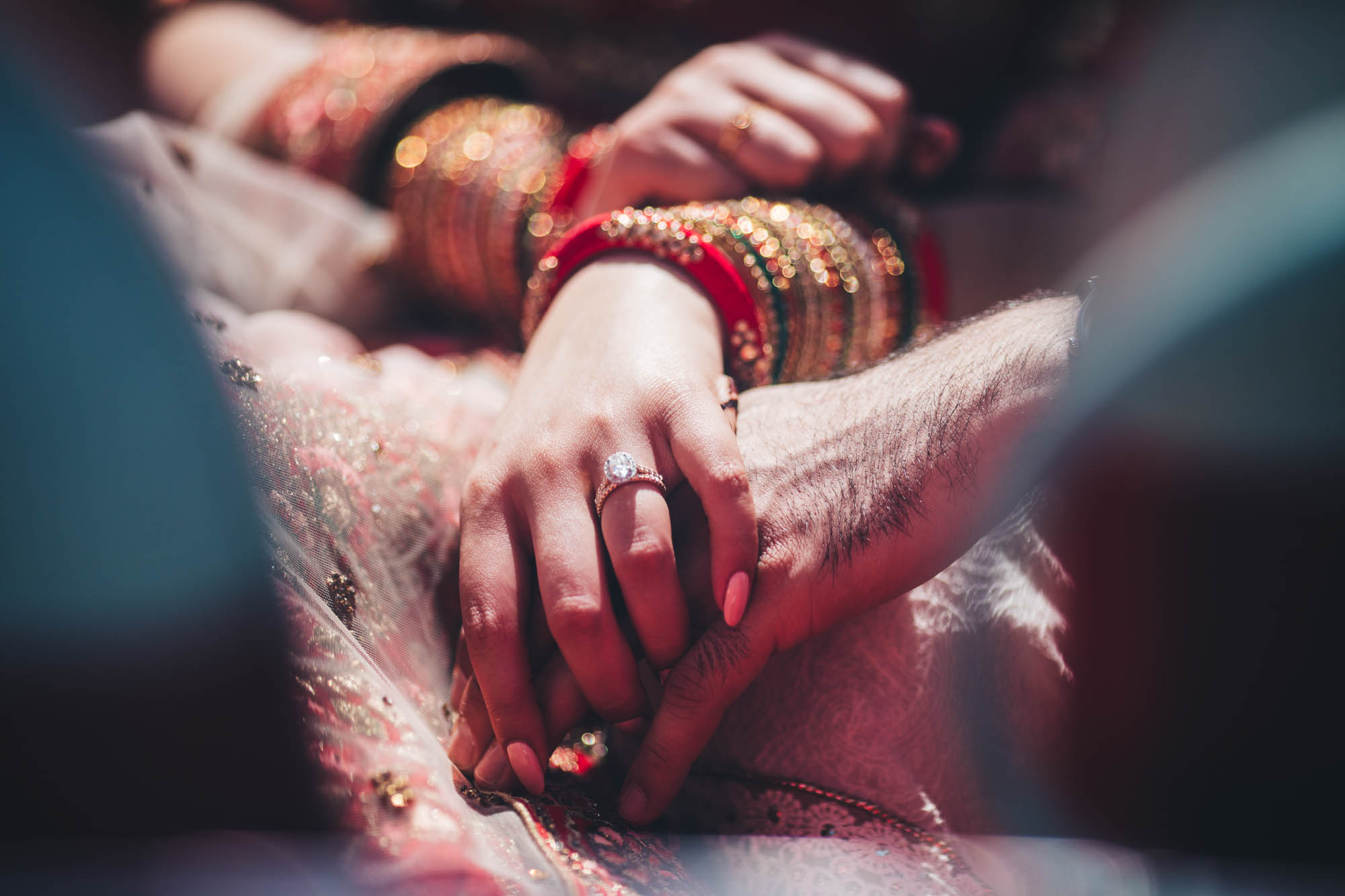 close up of wedding ring and Indian couple hold hands