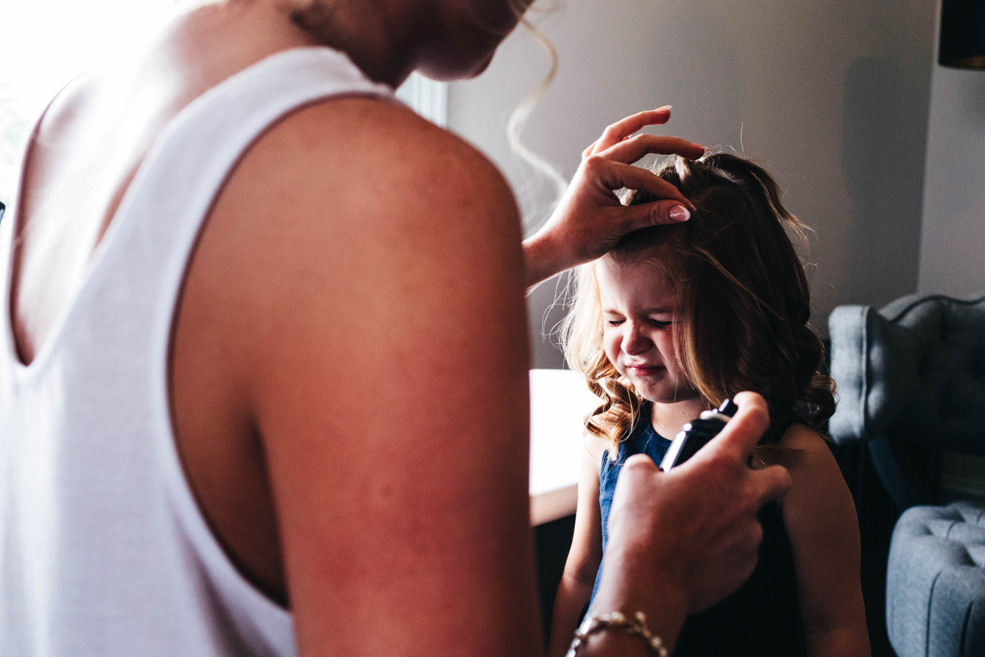 flower girl scrunches face up as she gets hairspray on her