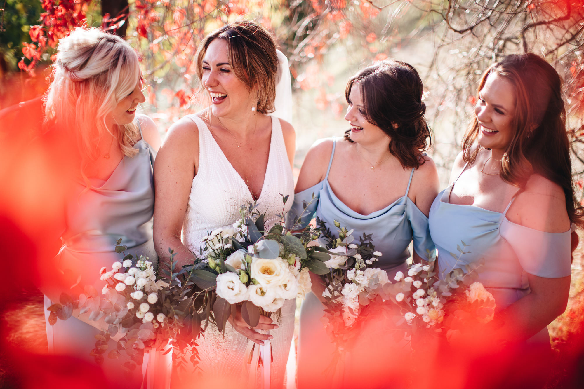 bride and maids laughing at each other holding their bouquets