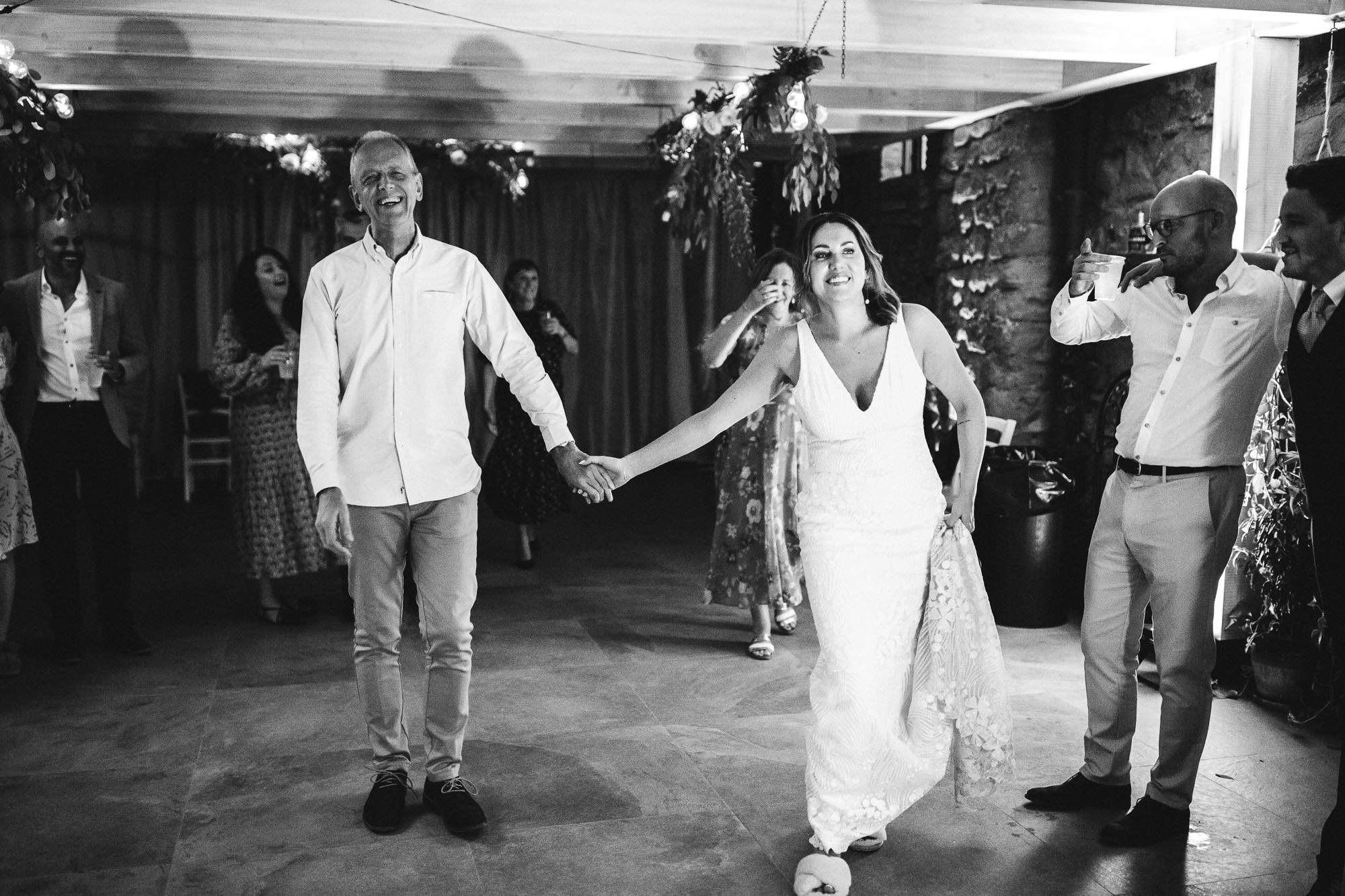 bride and father hold hands as they head towards the dancefloor together