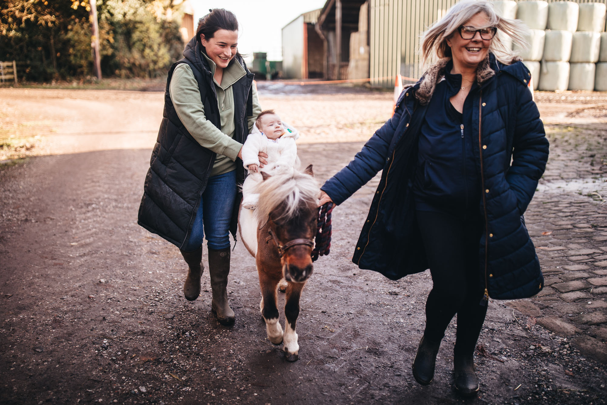baby rides on horse helped by mother and grandma