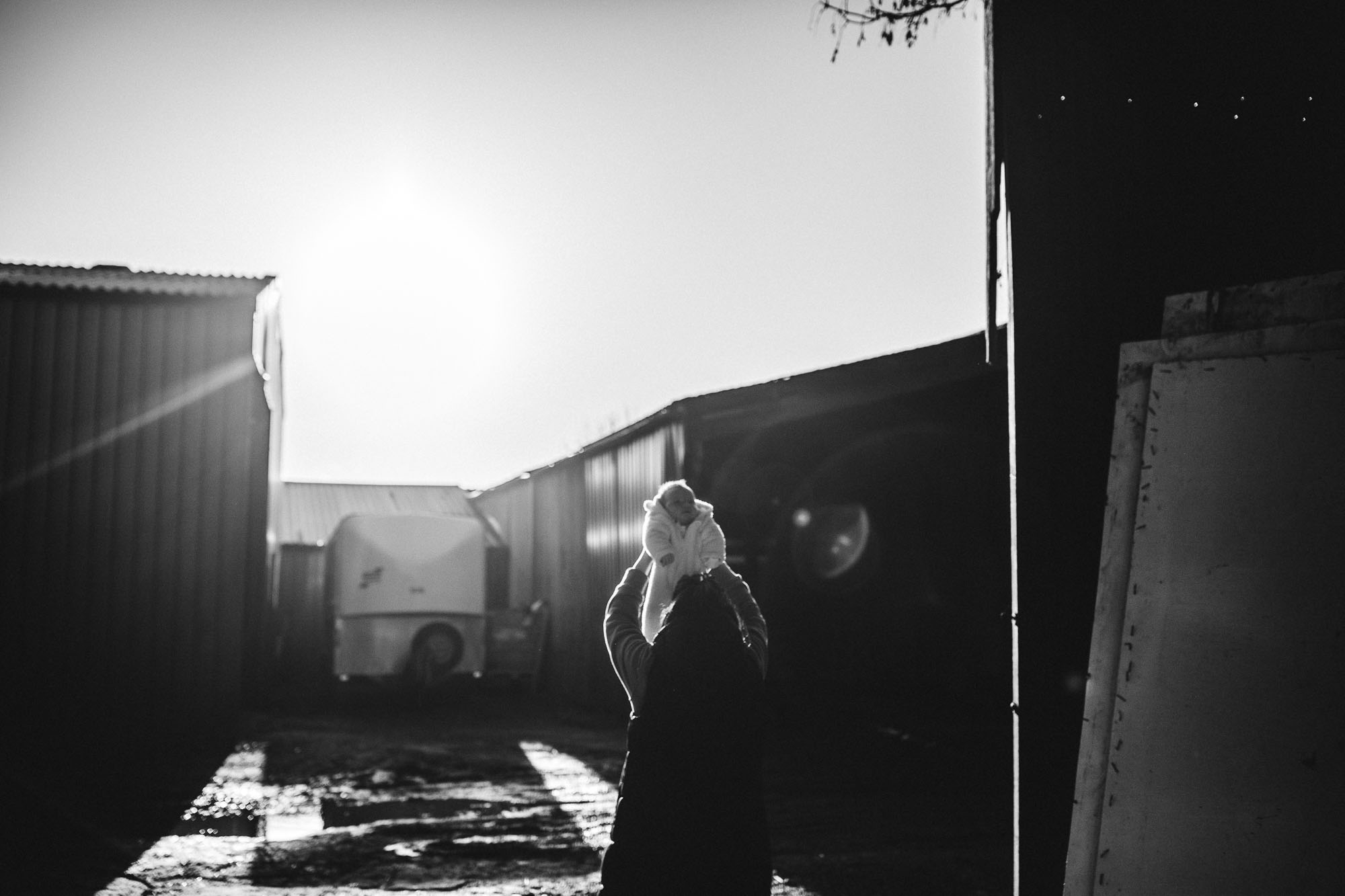 mother holds up baby in sunlight