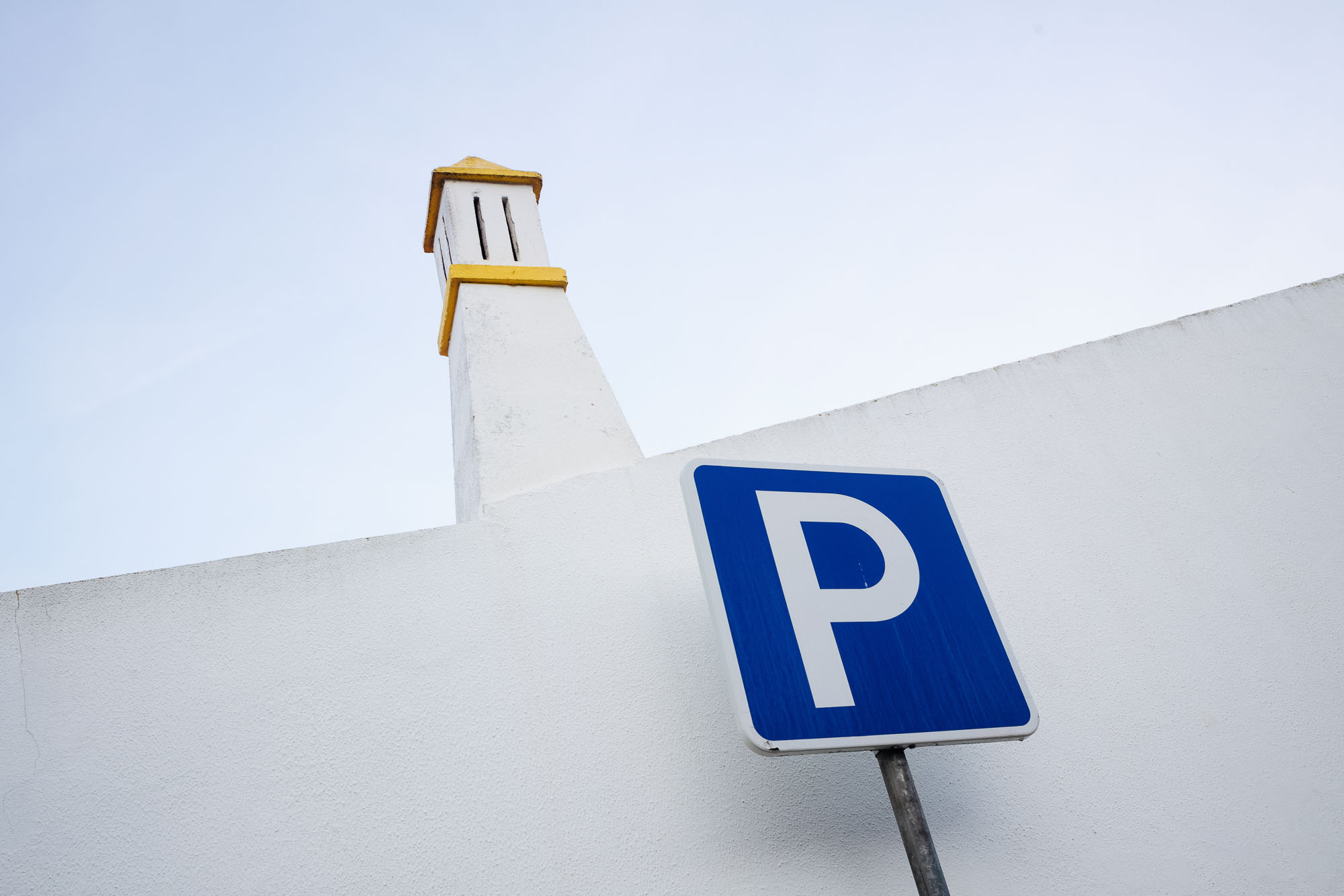 P for parking sign and chimney against sky