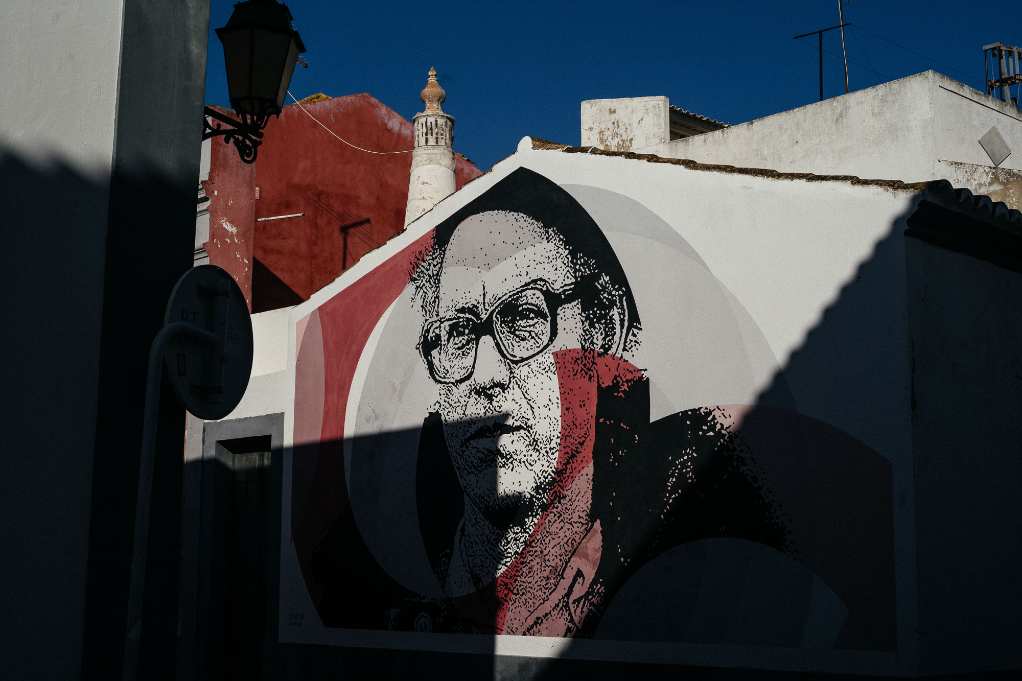 mural of man in glasses painted on side of building in faro