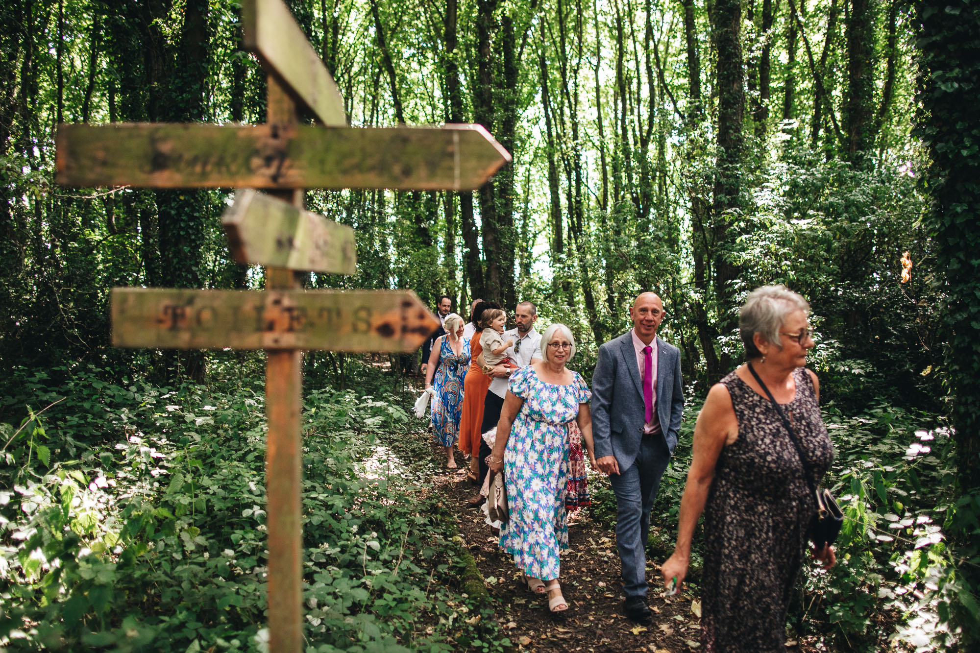 wedding guests make their way through the woods to the drinks reception