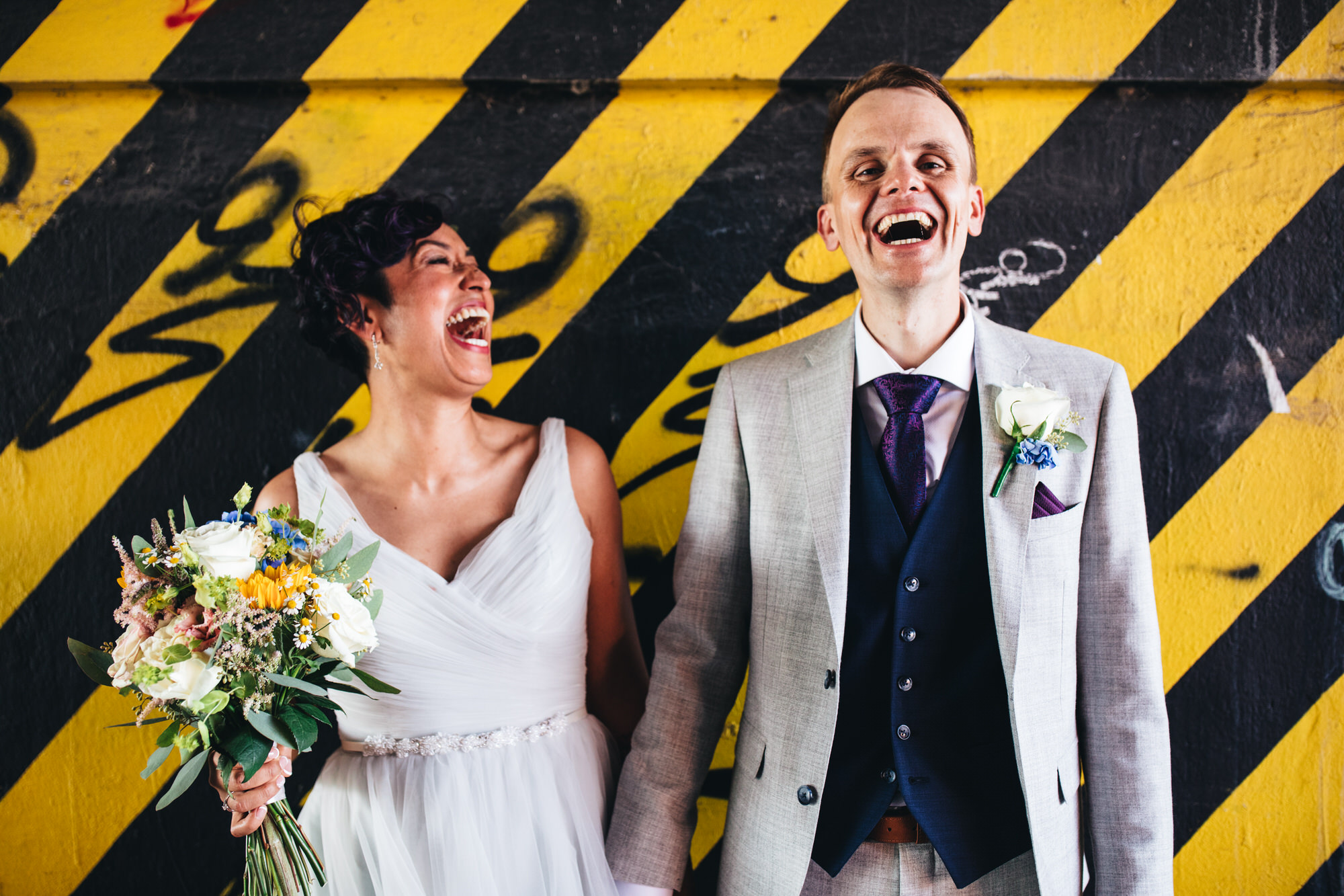 couple laugh against yellow and black striped wall