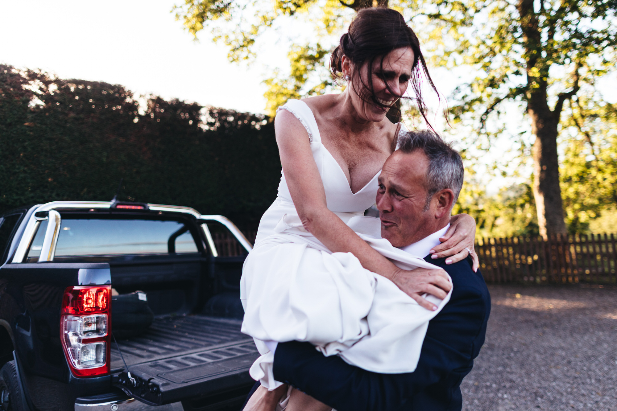 groom lifts bride off of the back of a pick up truck
