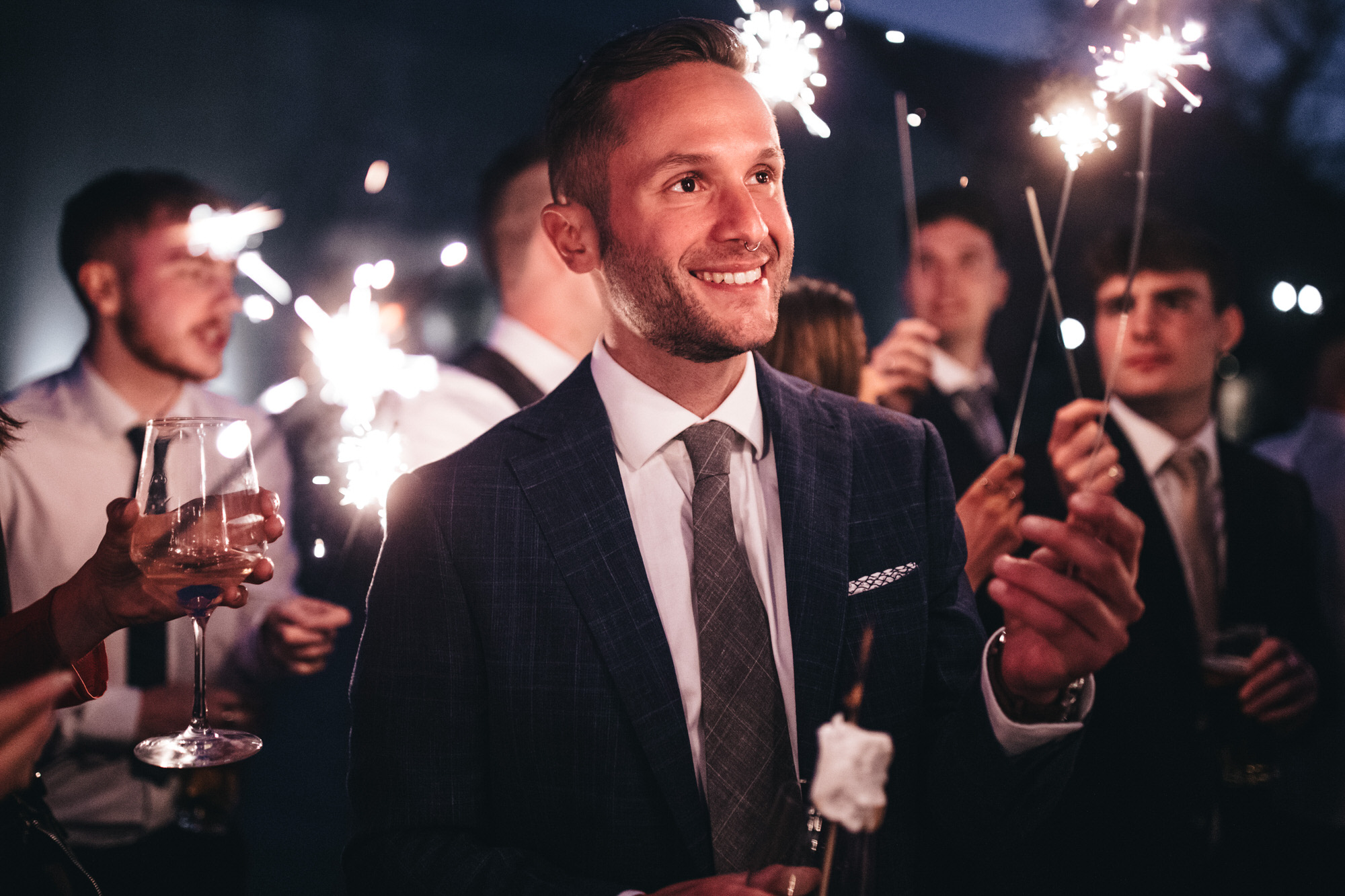 man smiles holding sparkler at night