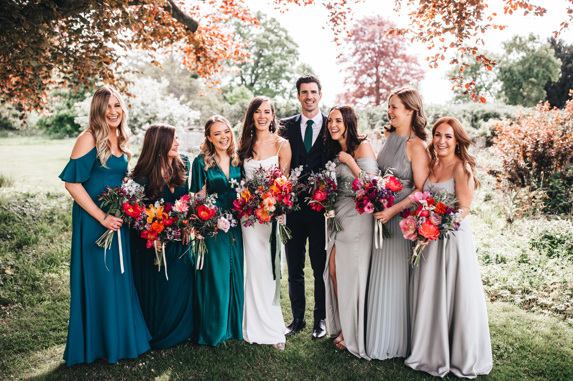 couple pose under a tree with the bridesmaids