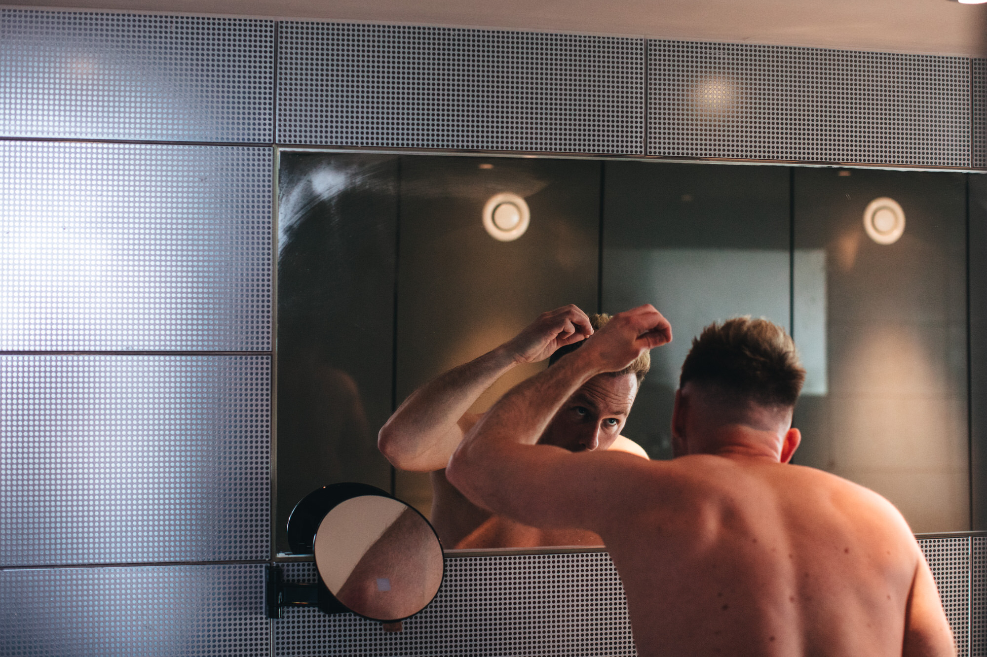 groom getting ready looking at himself in the mirror