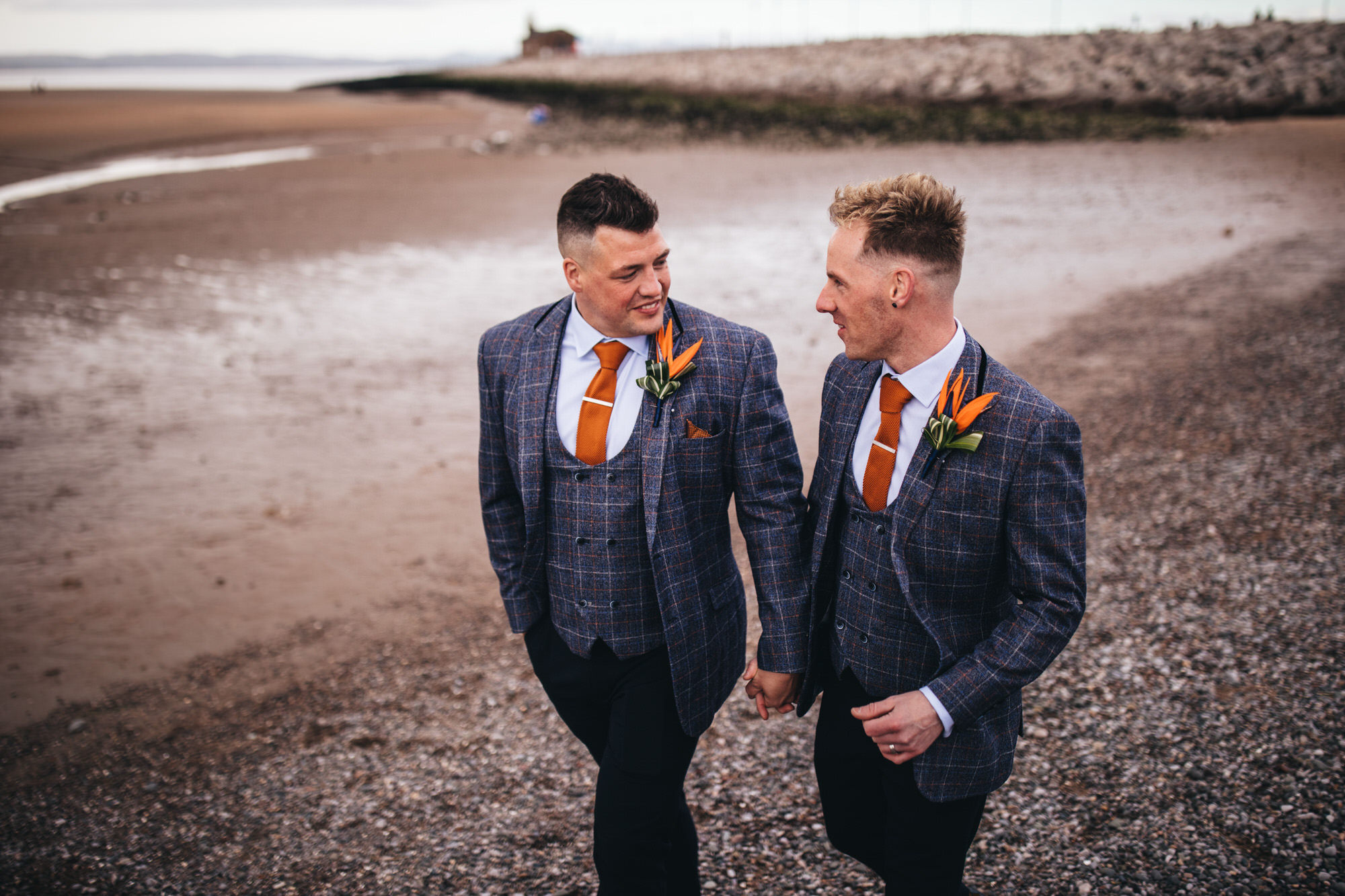 gay couple in matching suits walking on beach in morcambe