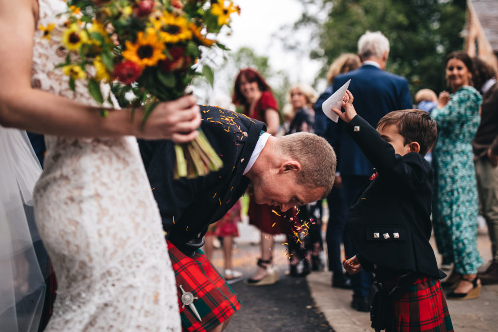page boy empties confetti cone on to groom